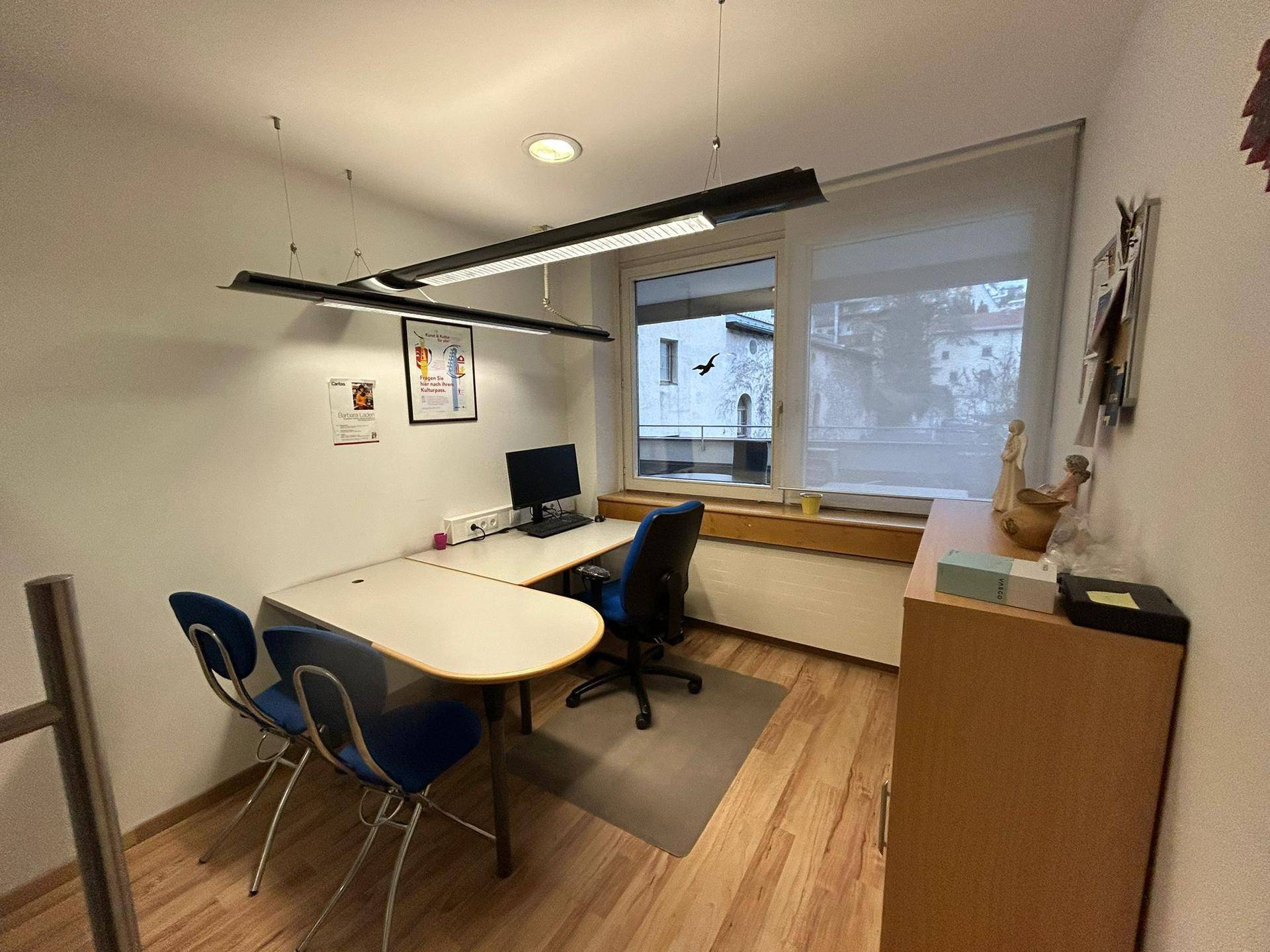 Kleines Büro mit Holzfußboden, zwei Arbeitsplätzen und einem Fenster mit Blick auf den Balkon.