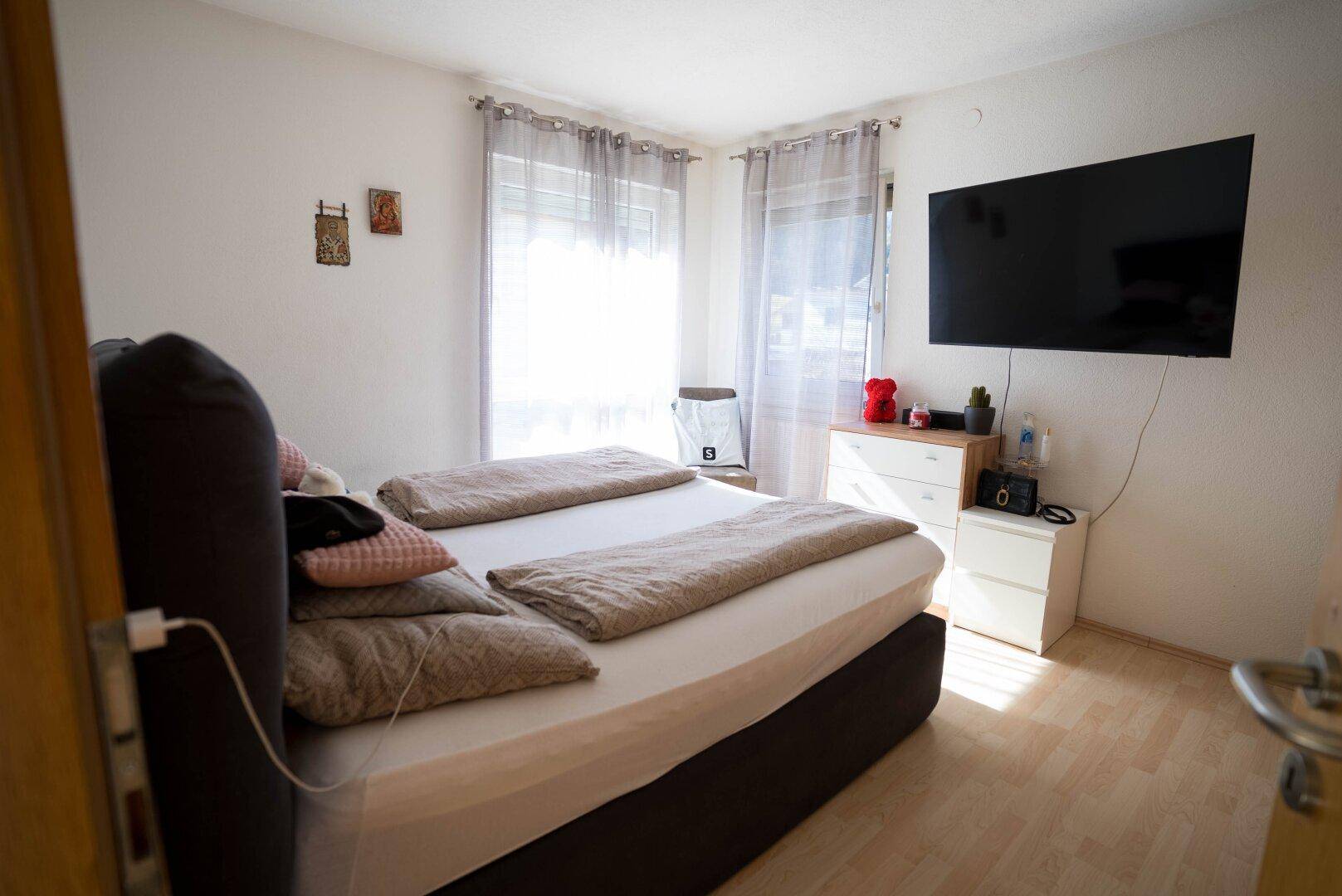 Gemütliches Schlafzimmer mit Doppelbett, Fernseher und Laminatboden.