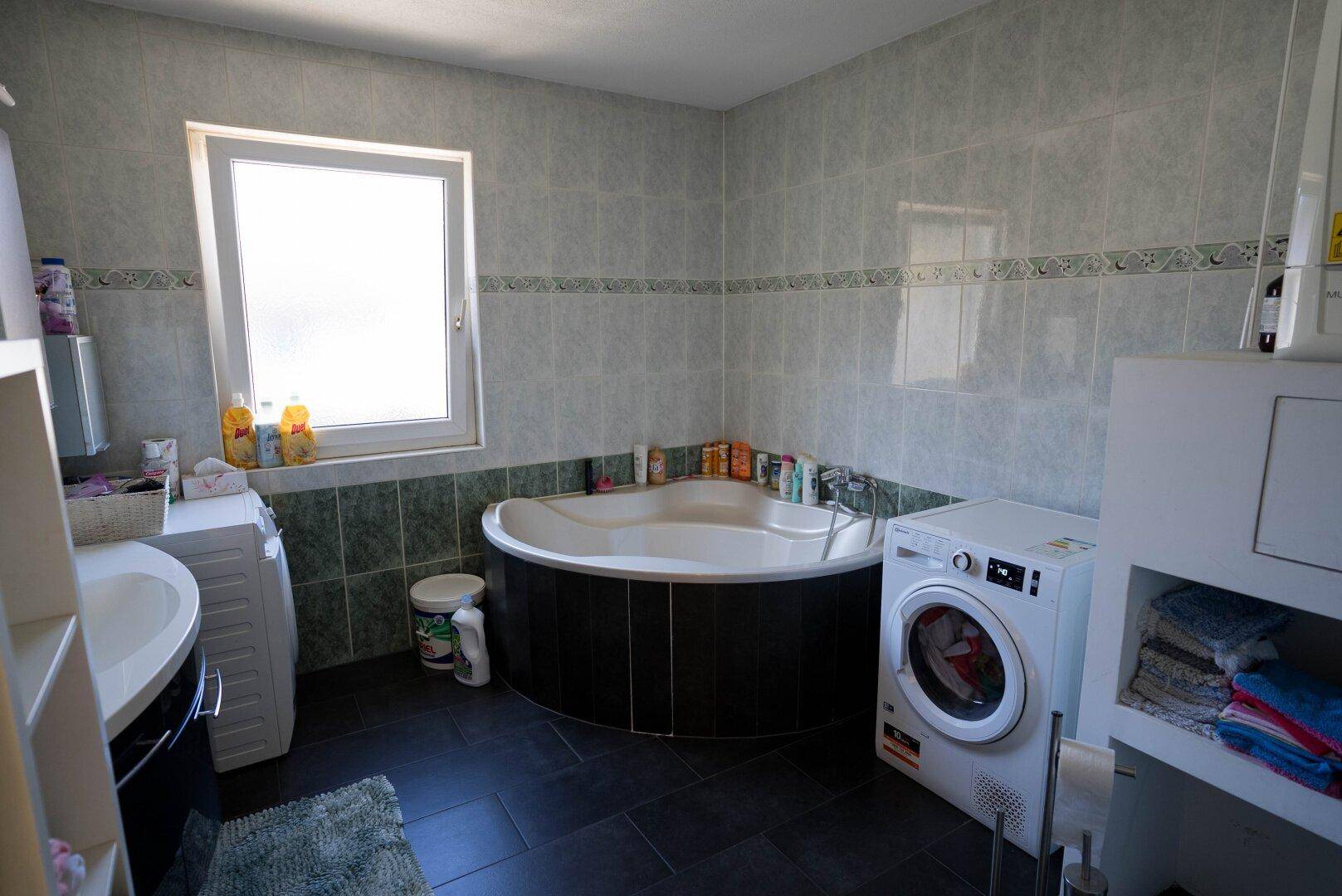 Geräumiges Badezimmer mit Eckbadewanne, Waschmaschine und Trockner.