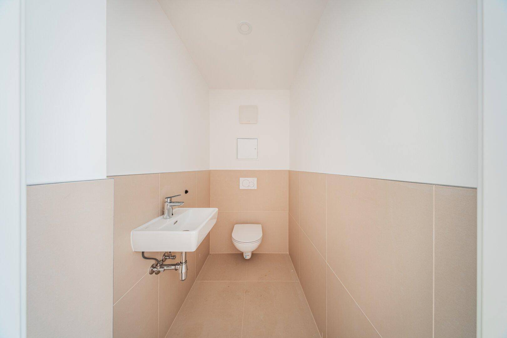 Kleines, modernes Gäste-WC mit Waschbecken und wandhängendem WC in neutralen Farbtönen.