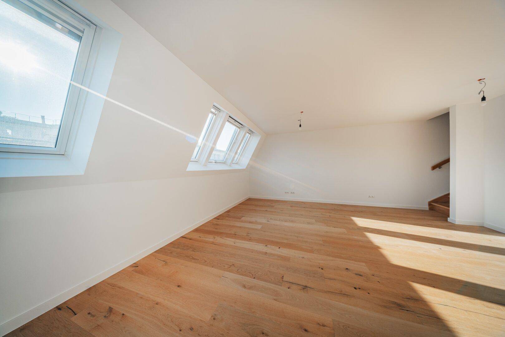 Heller Dachgeschossraum mit Holzboden und großen Dachfenstern, bereit zur individuellen Einrichtung.