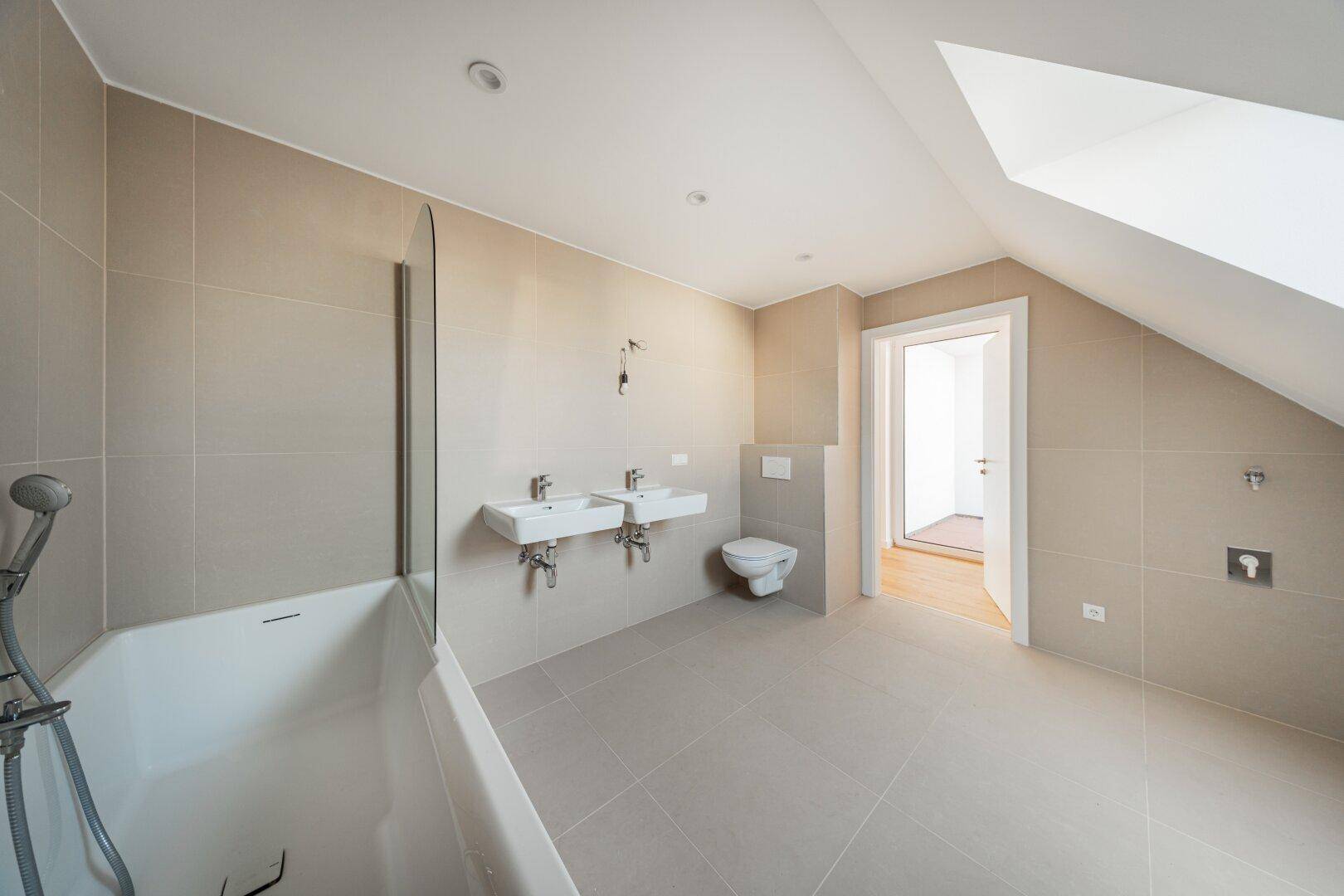 Geräumiges Badezimmer mit Badewanne, Doppelwaschbecken und wandhängendem WC in modernem Design.