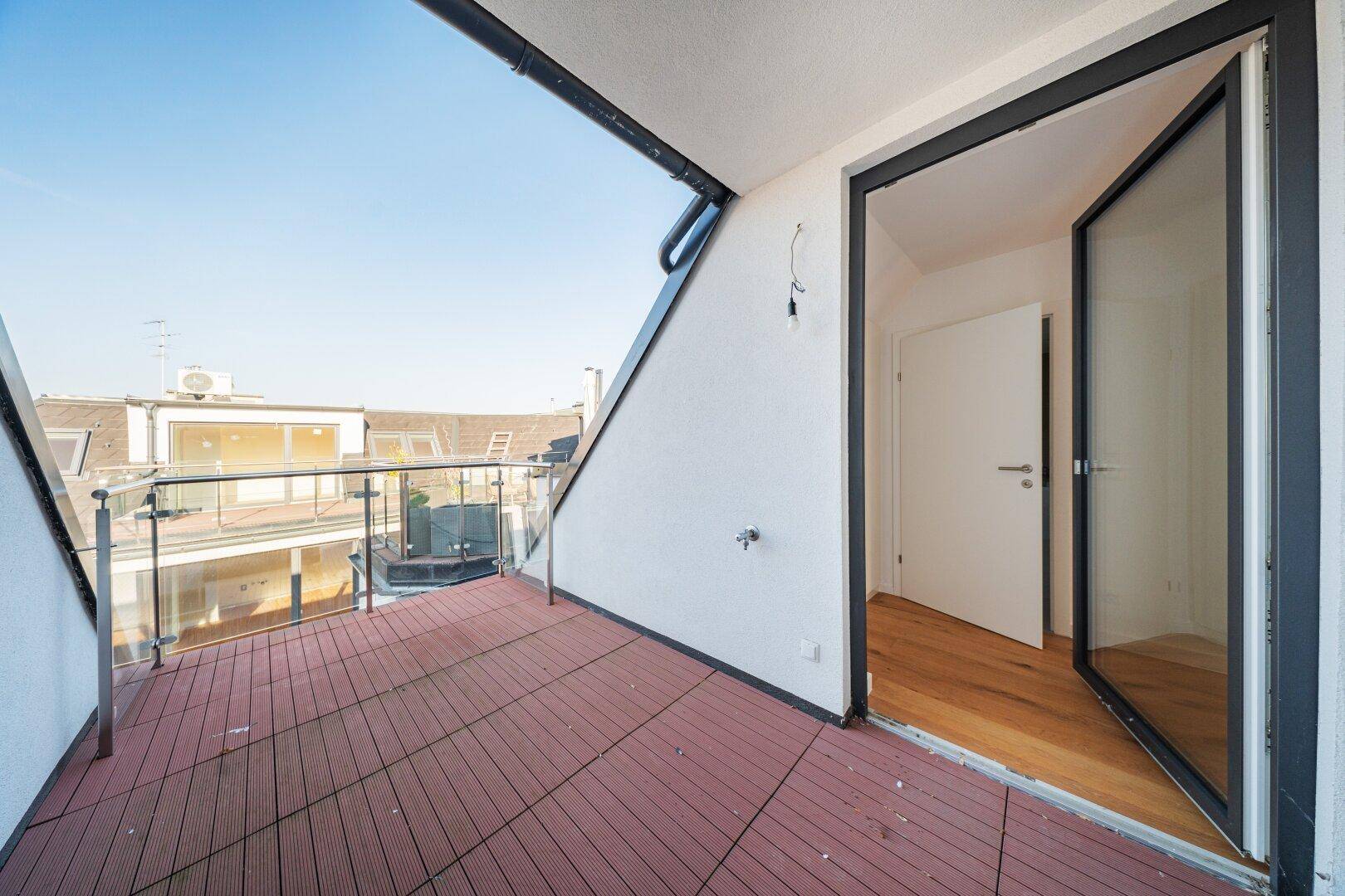 Geräumiger Balkon mit Holzboden und Glasgeländer, ideal für entspannte Stunden im Freien.