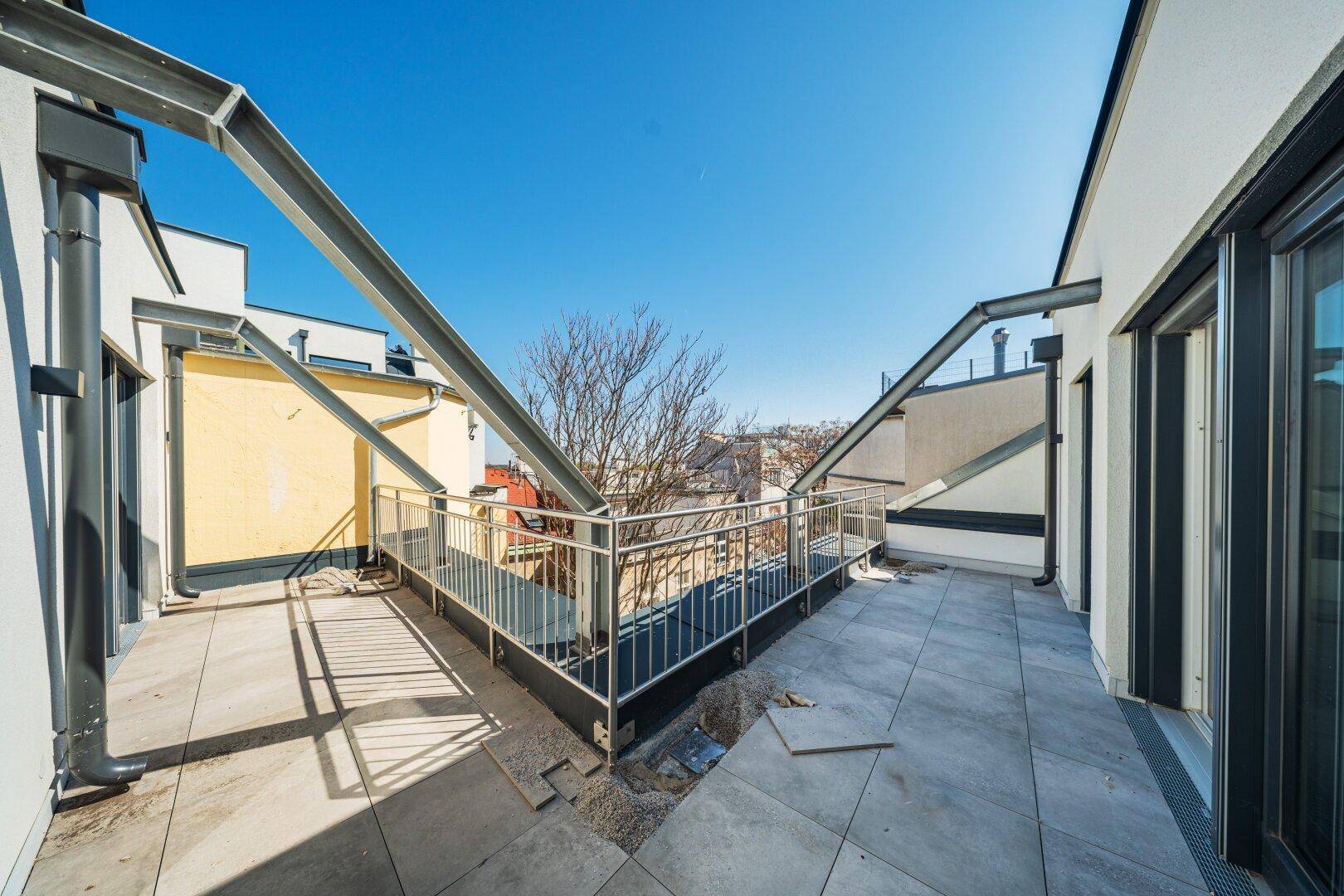 Geräumiger Balkon mit Fliesenboden und sichtbaren architektonischen Stützelementen.