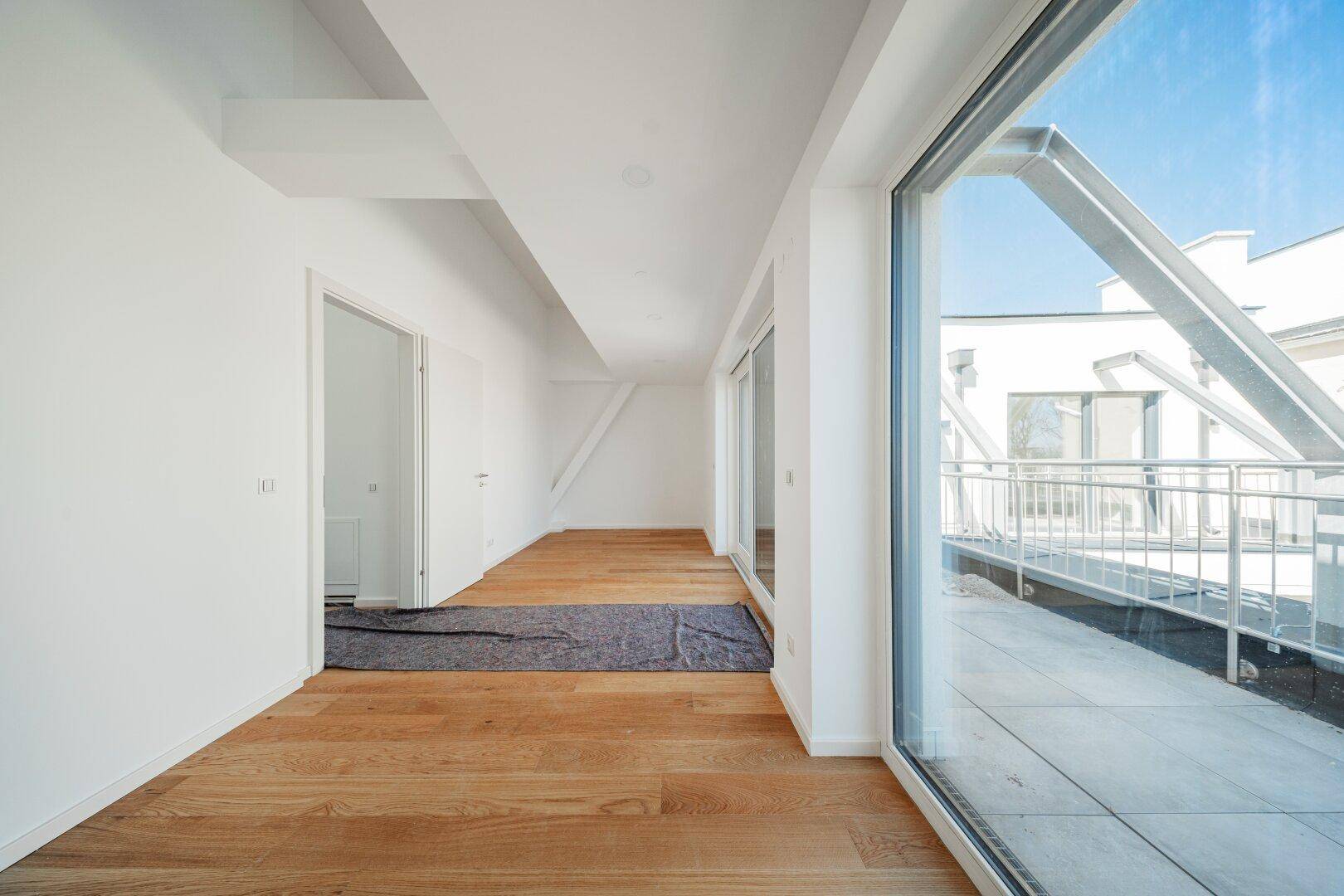 Großzügiger, heller Raum mit Holzboden und breiter Fensterfront, die eine weite Aussicht bietet.