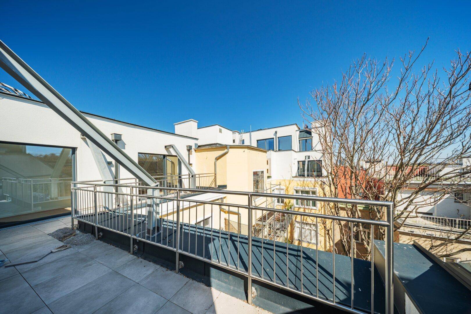 Geräumige Dachterrasse mit Metallgeländer und Blick auf die umliegenden Gebäude.