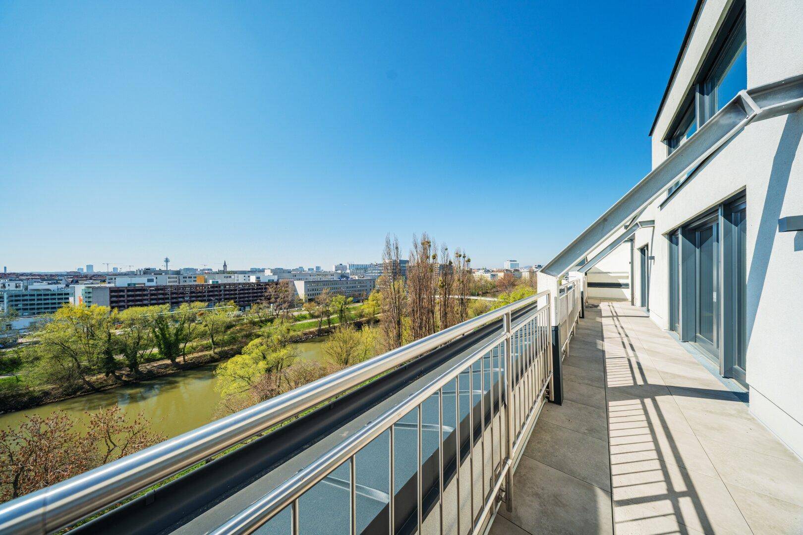 Lange Dachterrasse mit weitem Blick über einen Fluss und die Stadt, ideal für sonnige Tage.