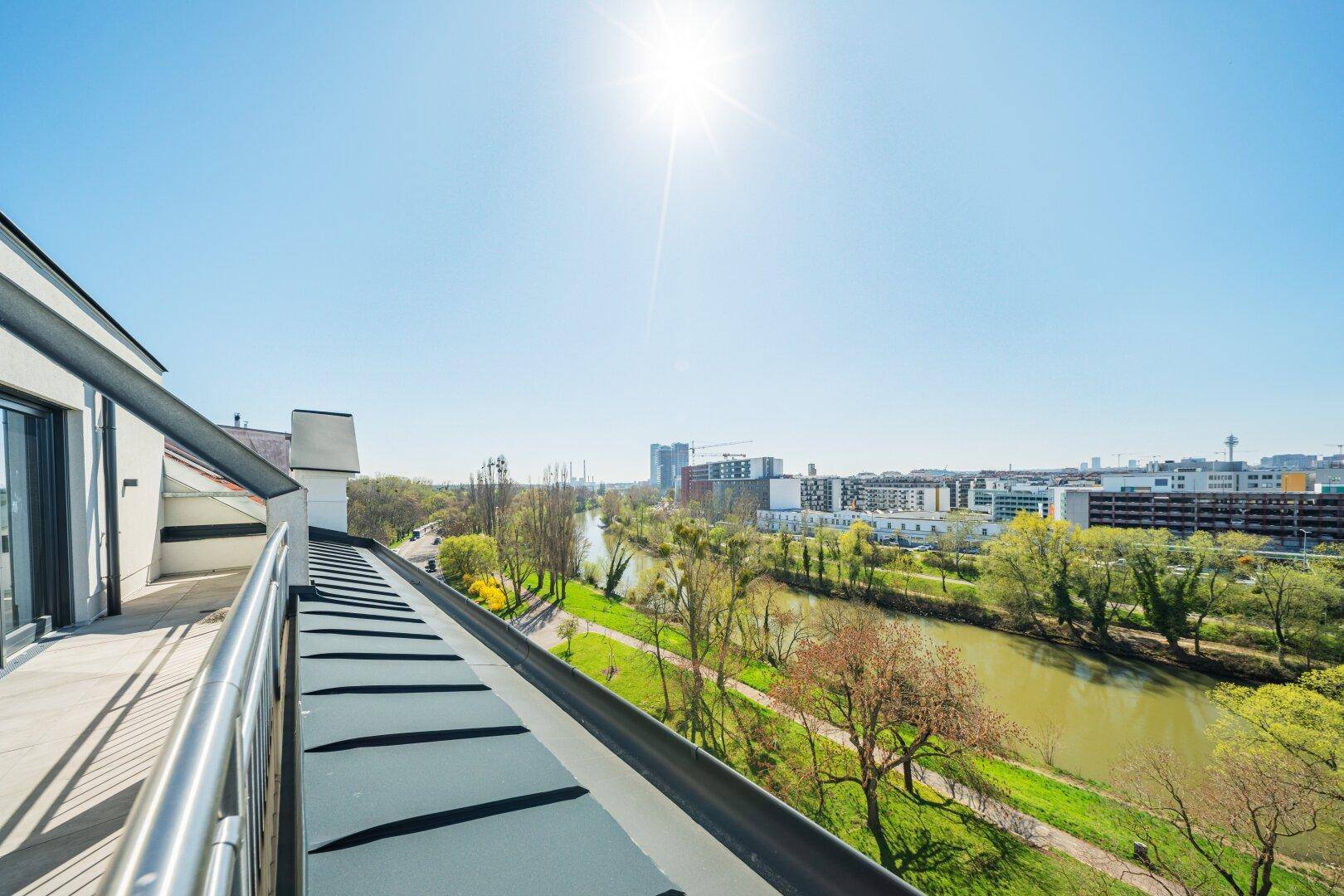 Sonniger Balkon mit weitem Blick über den Fluss und die Stadtlandschaft.