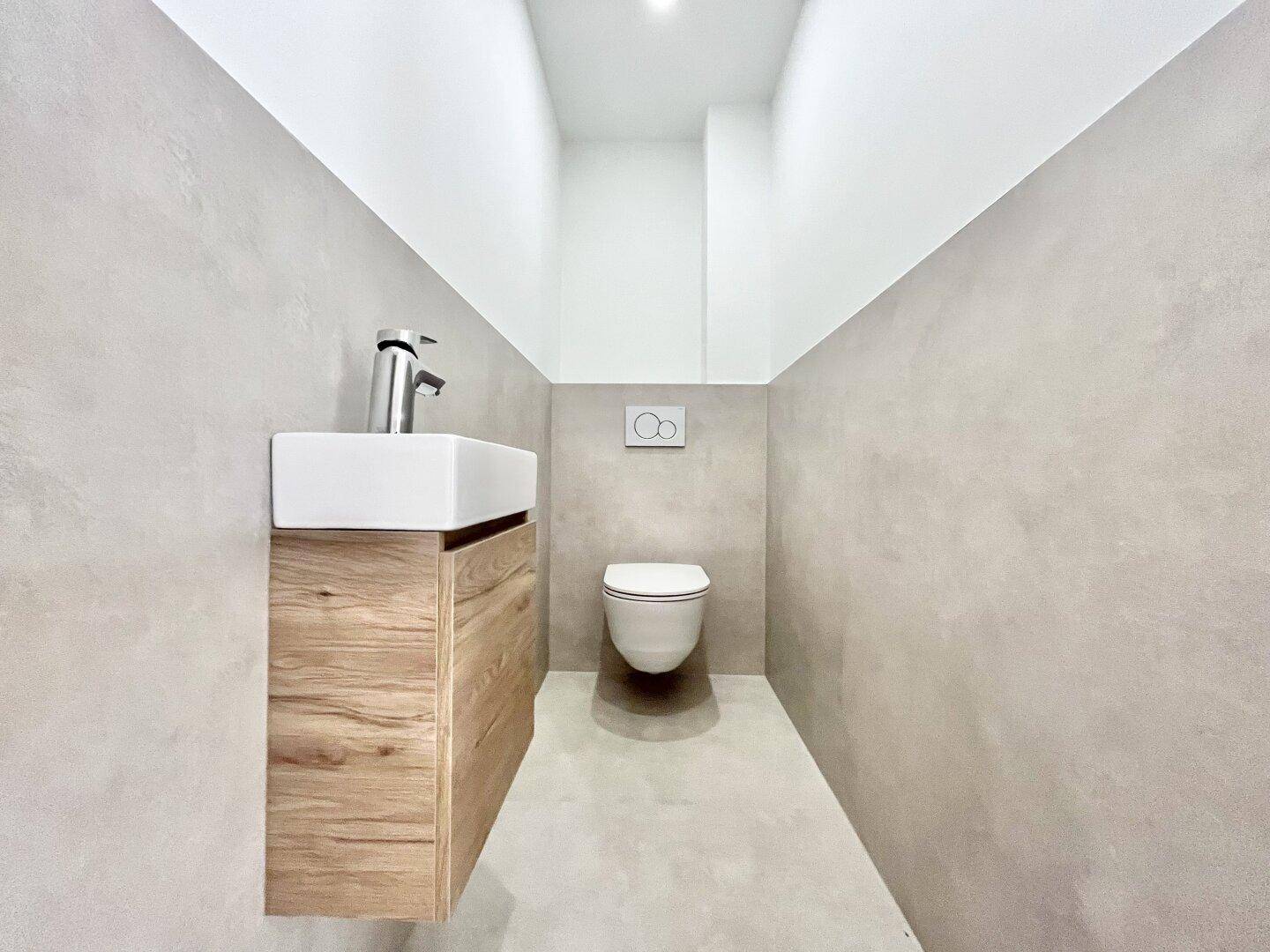 Kompaktes Gäste-WC mit wandhängender Toilette und modernem Waschbeckenunterschrank.