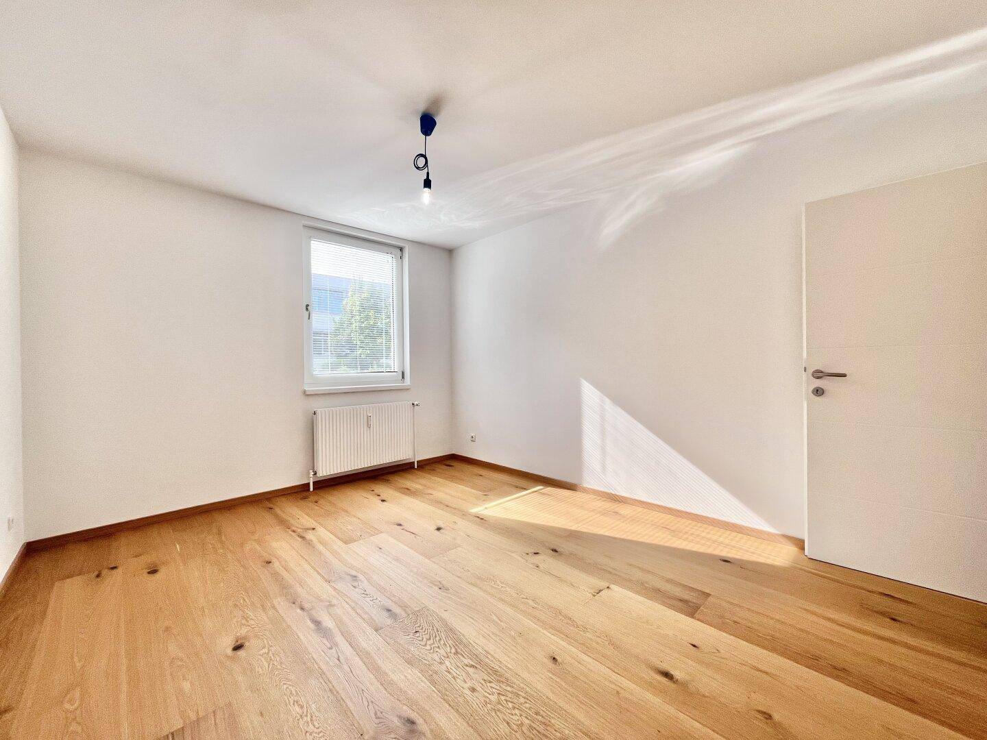 Ruhiges Schlafzimmer mit Holzboden, einem Fenster und viel natürlichem Licht.