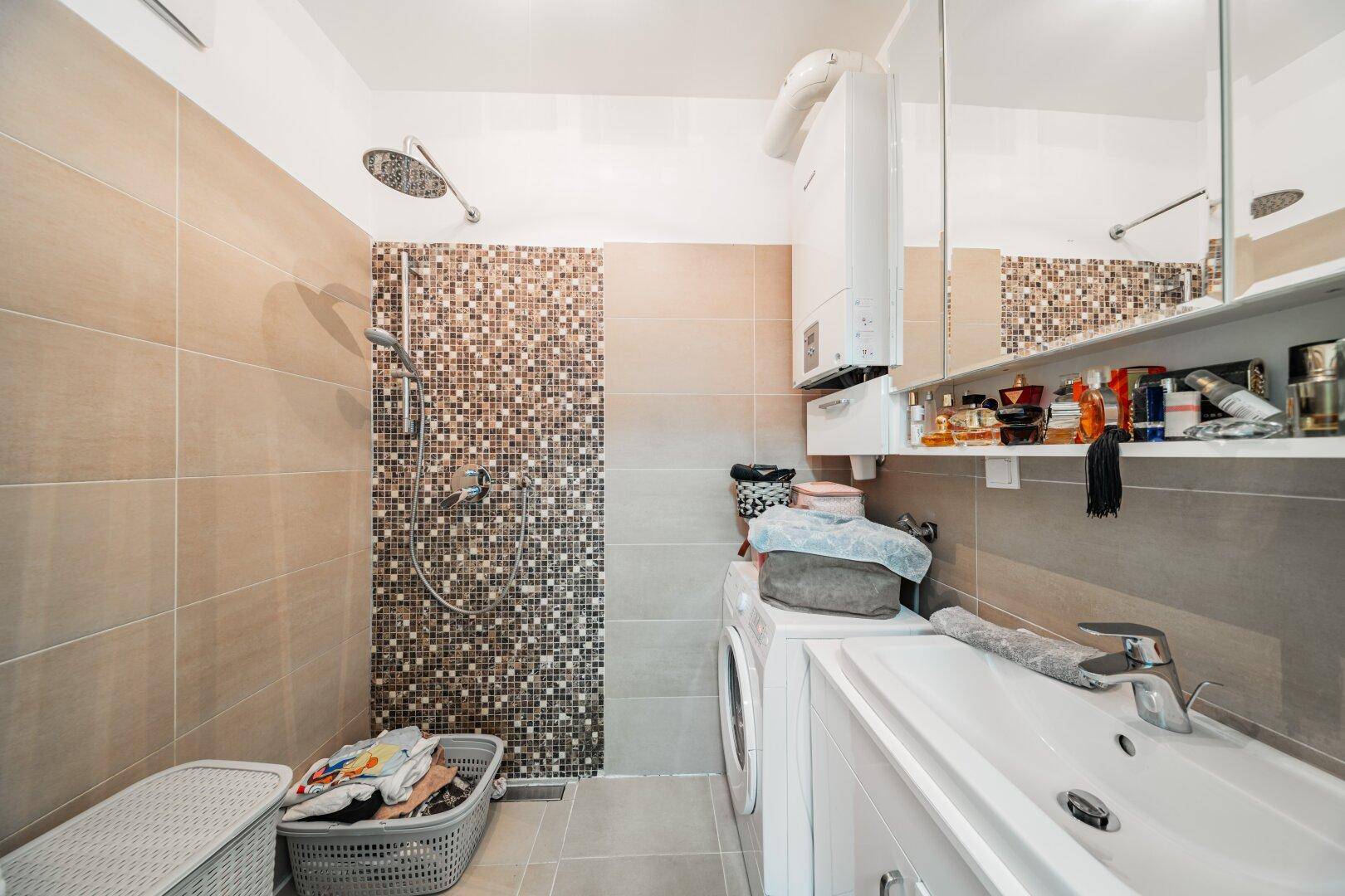 Modernes Badezimmer mit Duschbereich, Waschbecken und integrierter Waschmaschine und Trockner.
