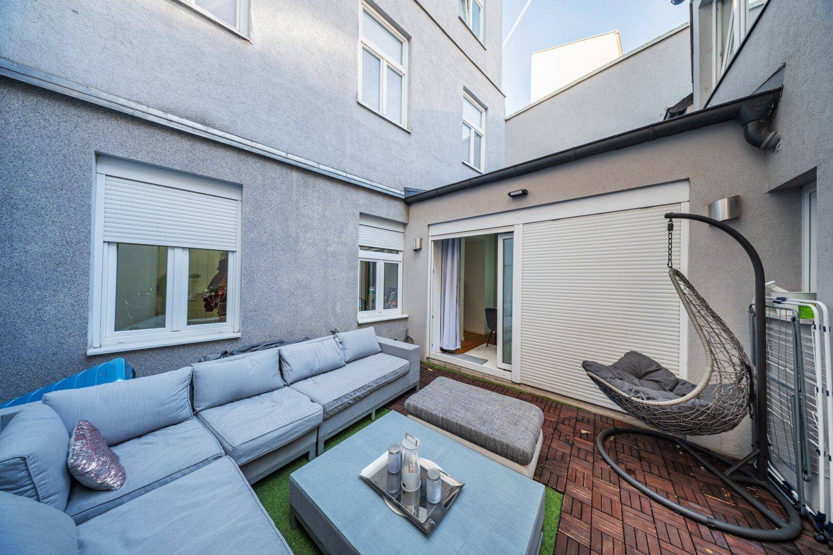 Gemütliche Außenterrasse mit Lounge-Möbeln und Schaukelstuhl, ideal zum Entspannen.