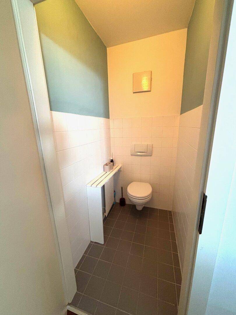 Separate Toilette mit Wand-WC, Fliesen und farbiger Wandgestaltung.