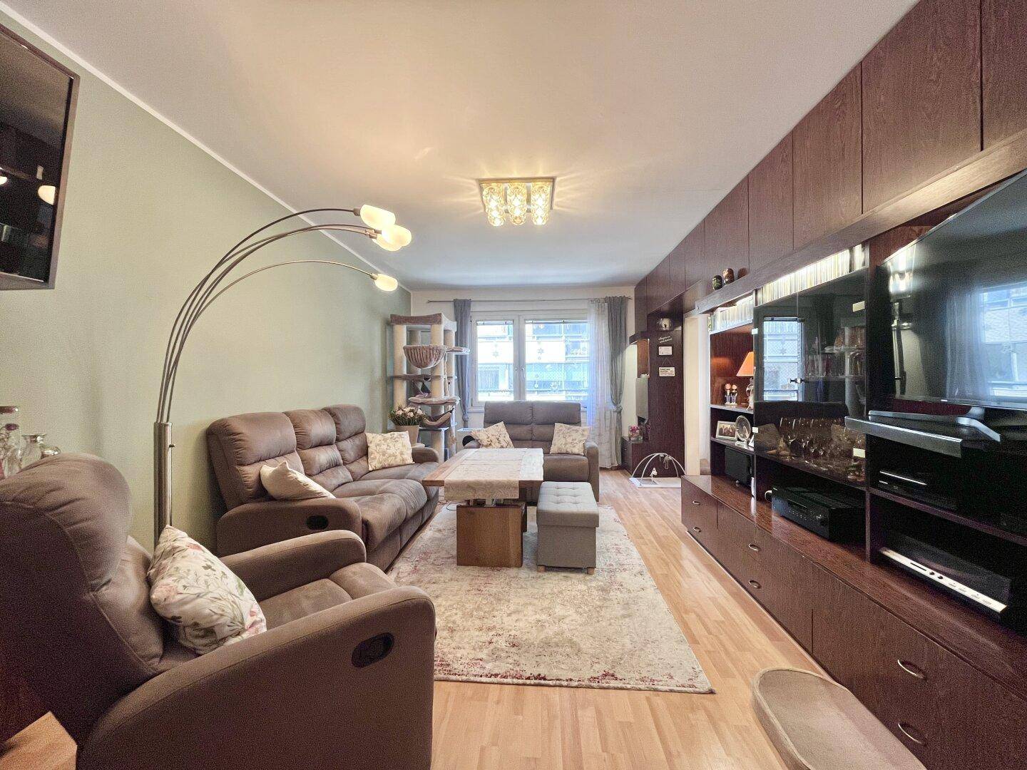 Gemütliches Wohnzimmer mit bequemen Sofas, Holzboden und einem großen TV-Möbel.