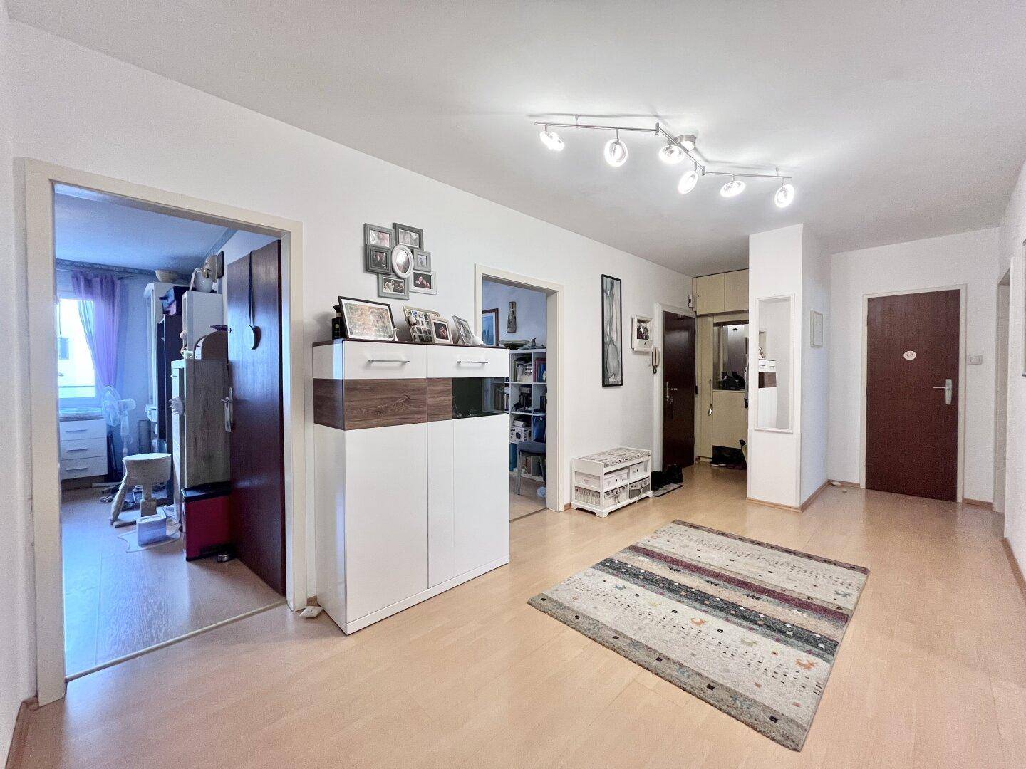 Geräumiger Flur mit hellem Holzboden, Schuhschrank und Blick in angrenzende Zimmer.