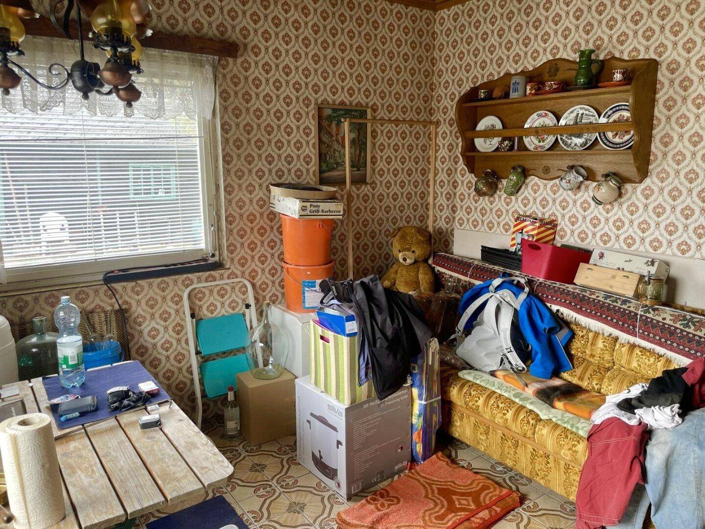 Gemütlicher Wohnraum mit Sofa, gemusterter Tapete und dekorativem Wandregal.