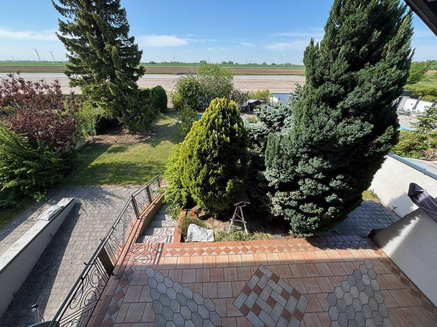 Weitläufiger Blick von der Terrasse über den grünen Garten und die umliegende Landschaft.