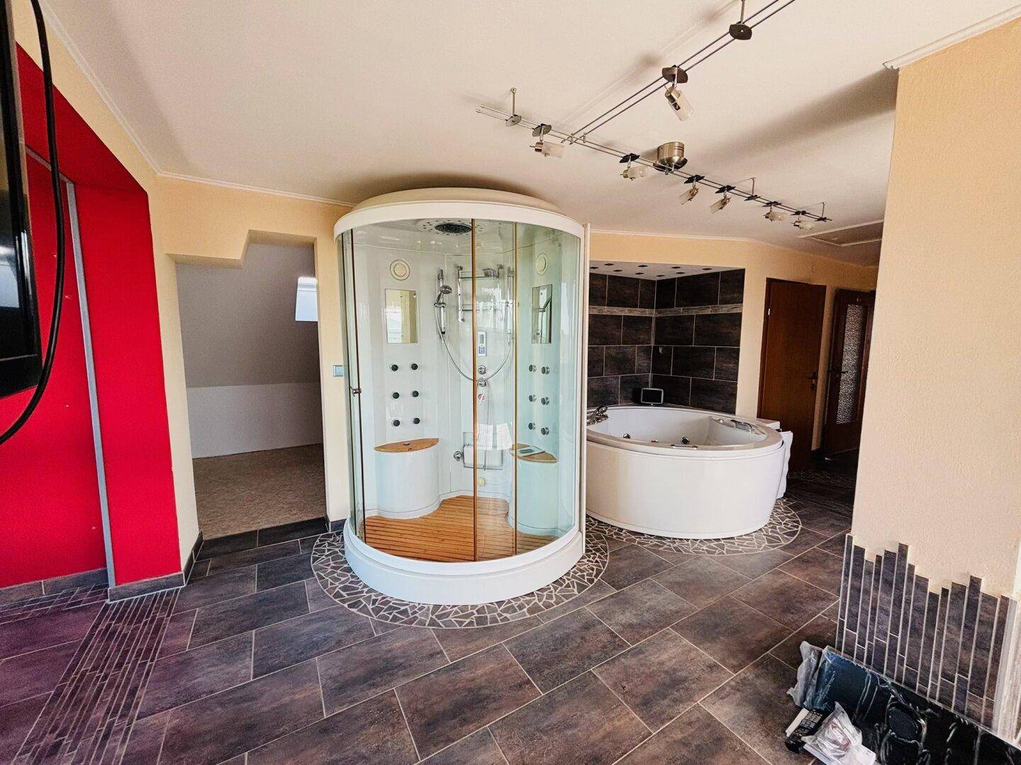 Wellnessbereich im Dachgeschoss mit moderner Duschkabine und großem Whirlpool.