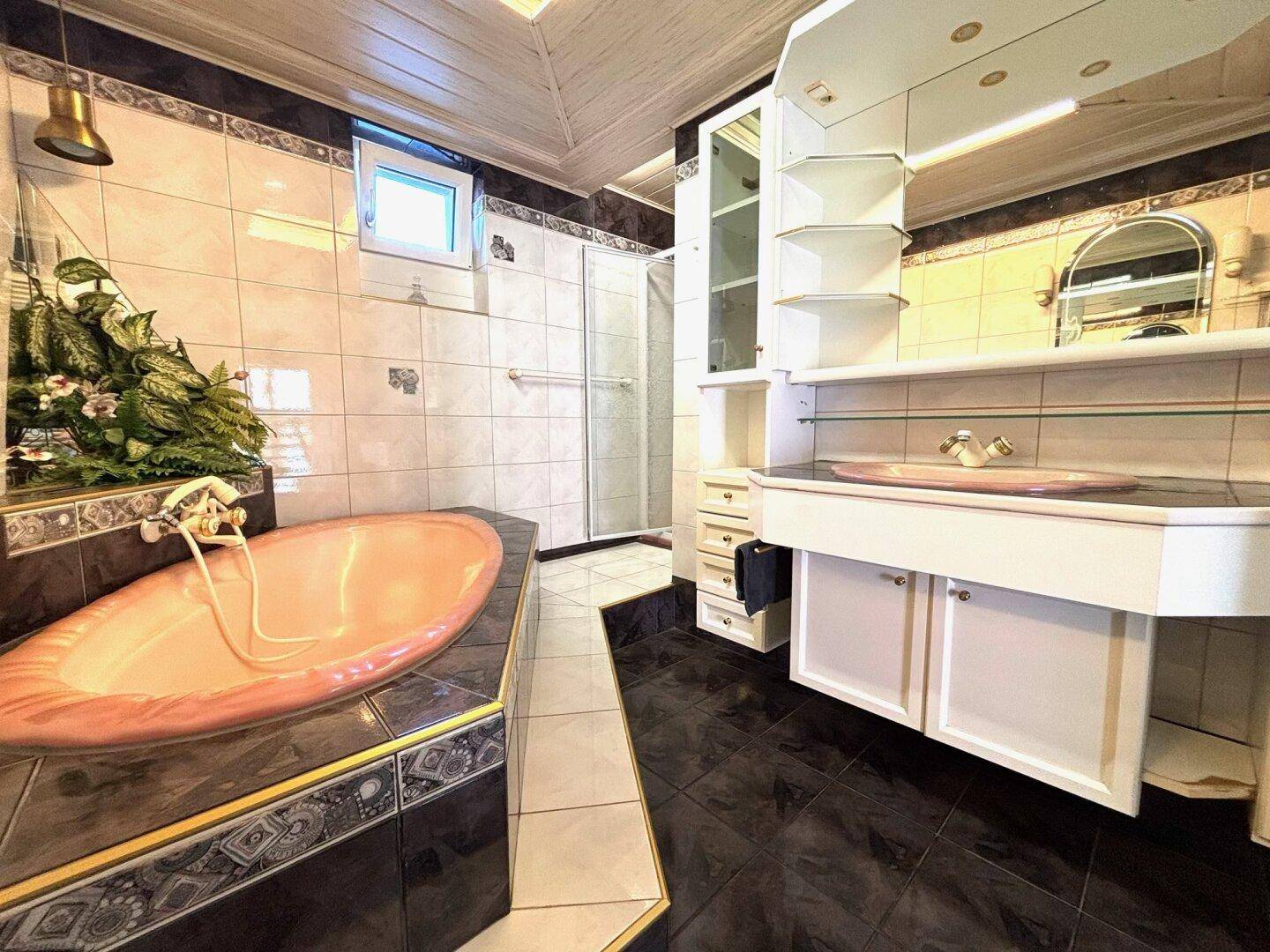 Geräumiges Badezimmer mit eingebauter Badewanne, Dusche und Waschtisch mit Spiegelschrank.