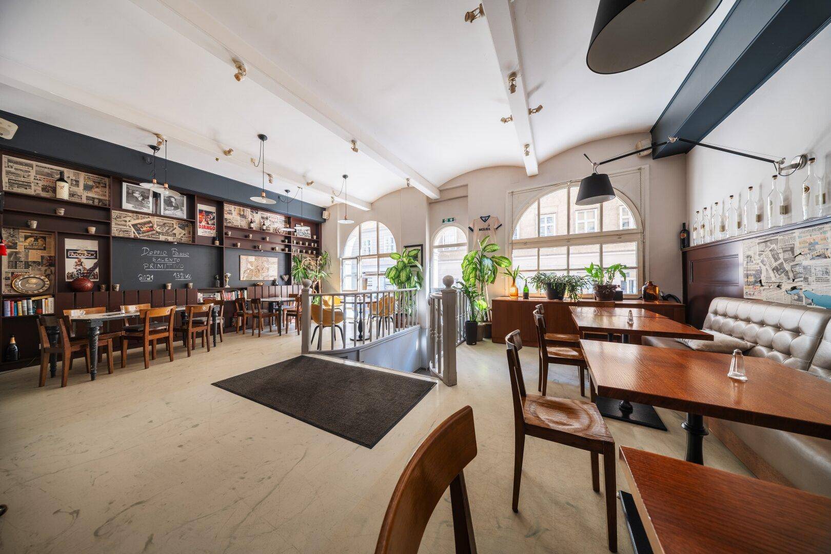 Heller Restaurantraum mit Holztischen, gepolsterten Bänken und dekorativen Wandelementen.
