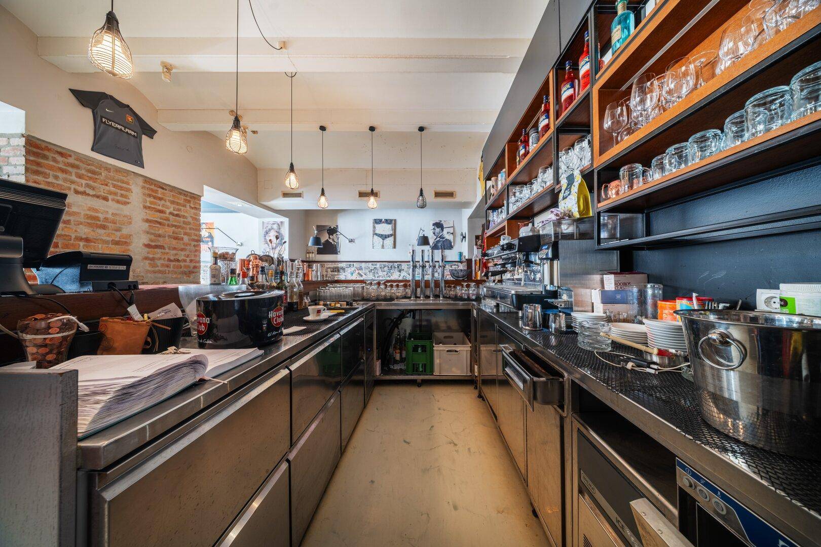 Professionelle Edelstahlküche mit Arbeitsflächen, Spülbecken und Regalen für Gastronomiebedarf.