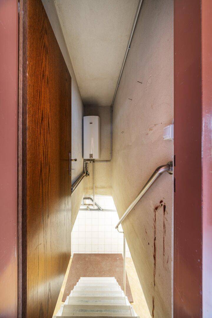 Treppenabgang zum Keller mit weißem Boiler und Handlauf.