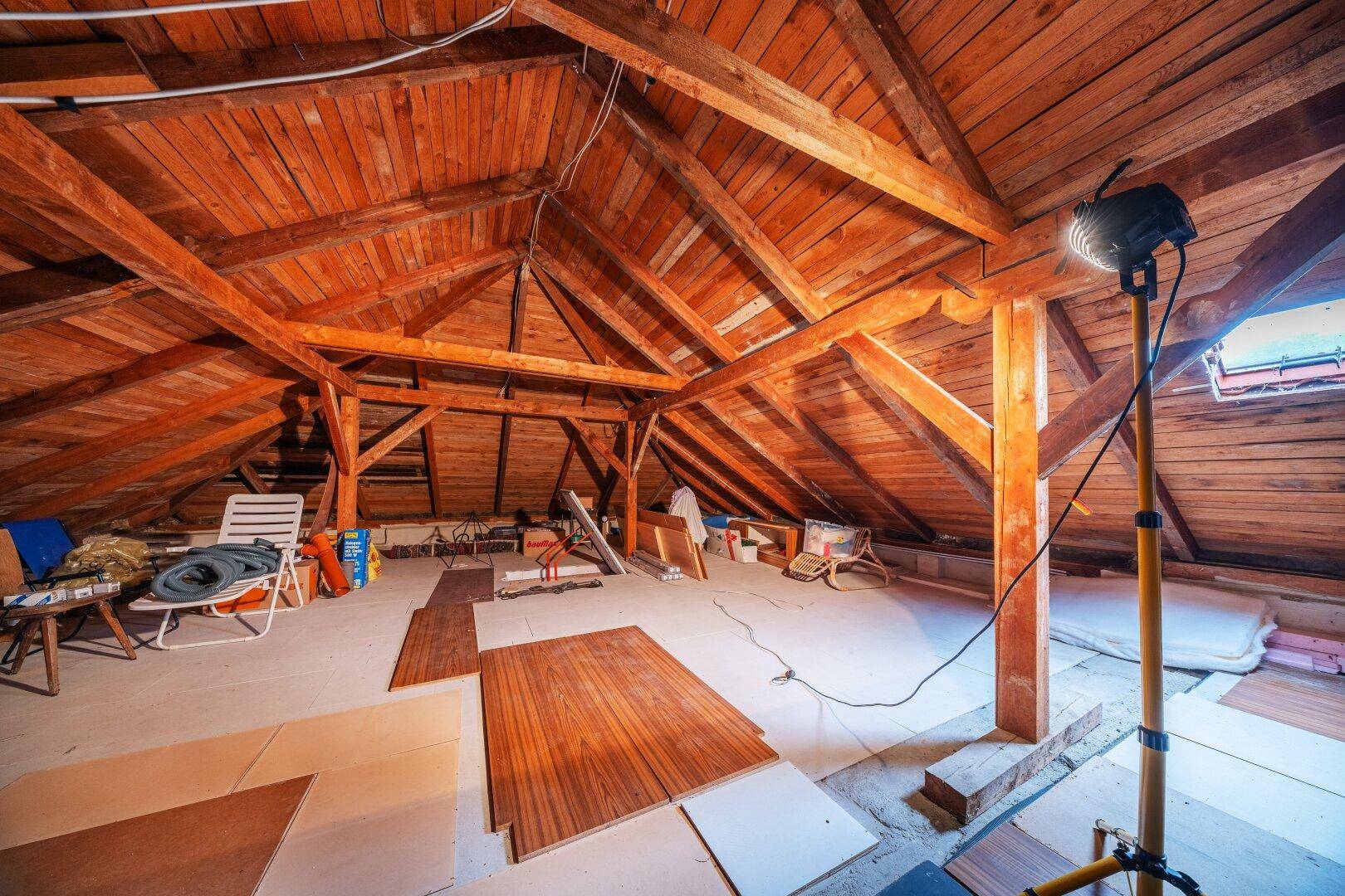 Großer Dachboden mit Holzbalken, Dachfenster und viel Stauraum.