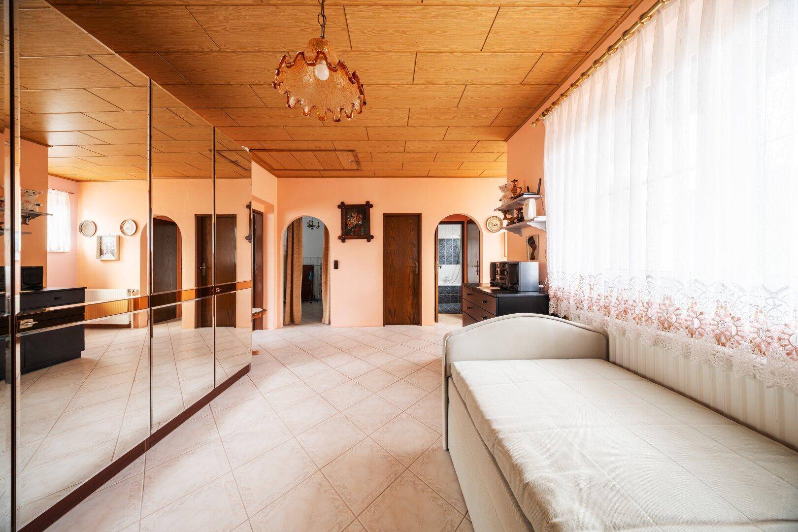 Geräumiges Zimmer mit Fliesenboden, Spiegelschränken und Einzelbett.