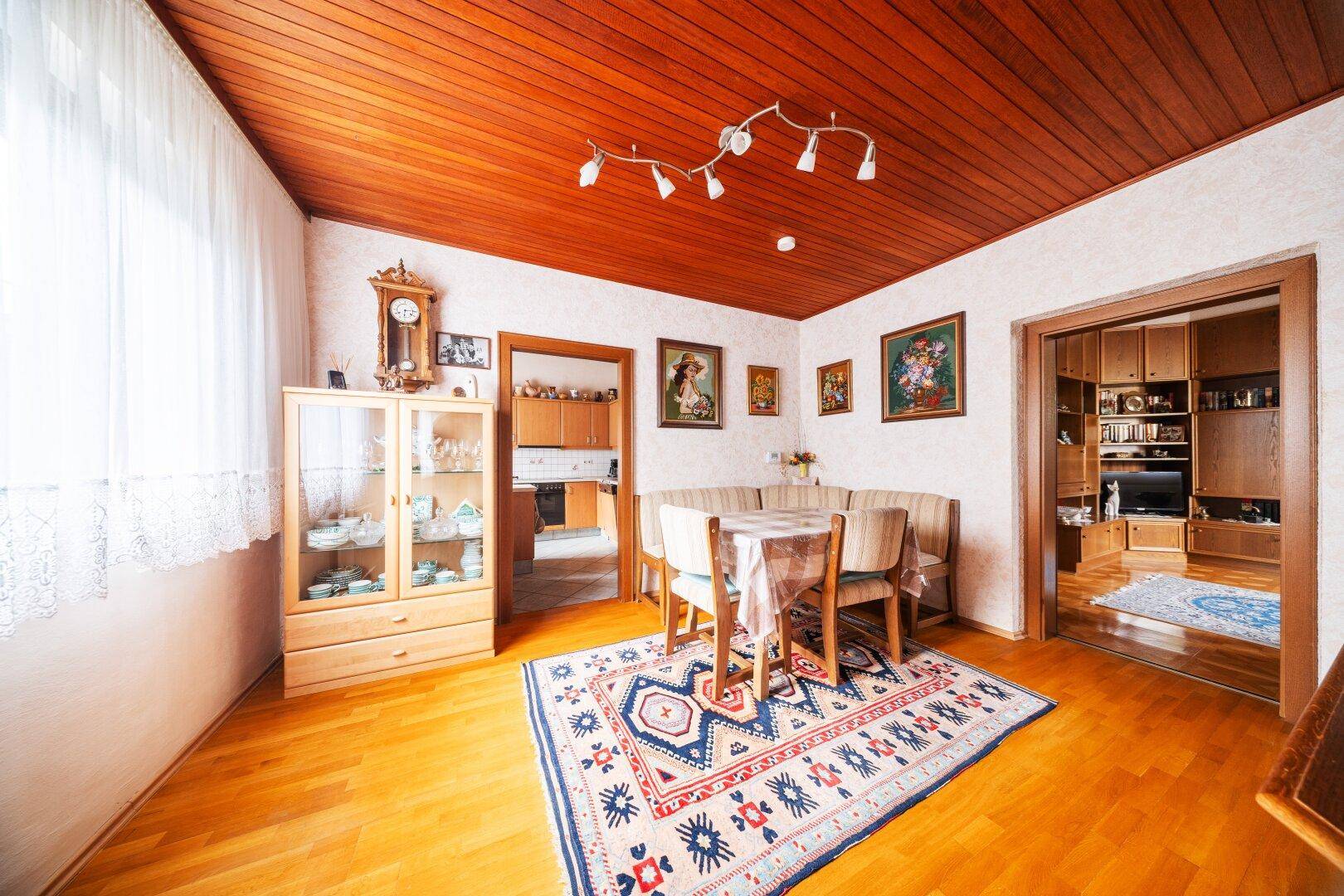 Esszimmer mit Holztäfelung an der Decke, Esstisch und Sitzbank in traditionellem Stil.