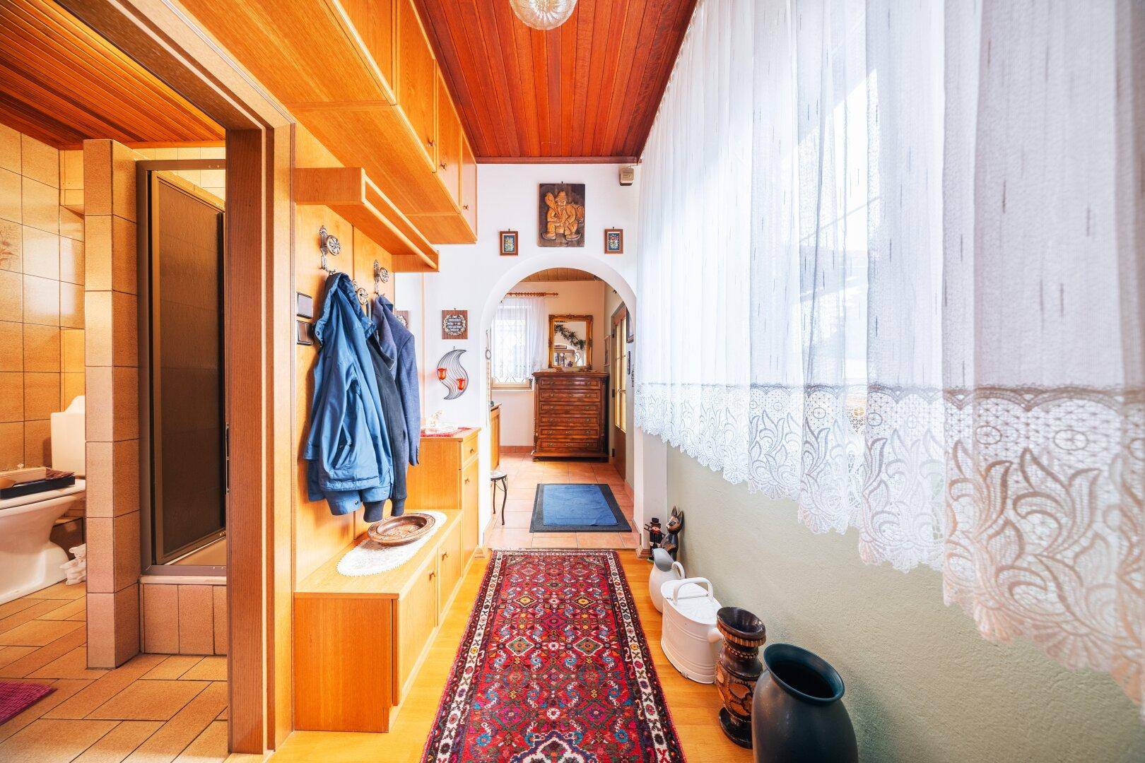 Flur mit Garderobe, Teppich und Zugang zu weiteren Räumen.