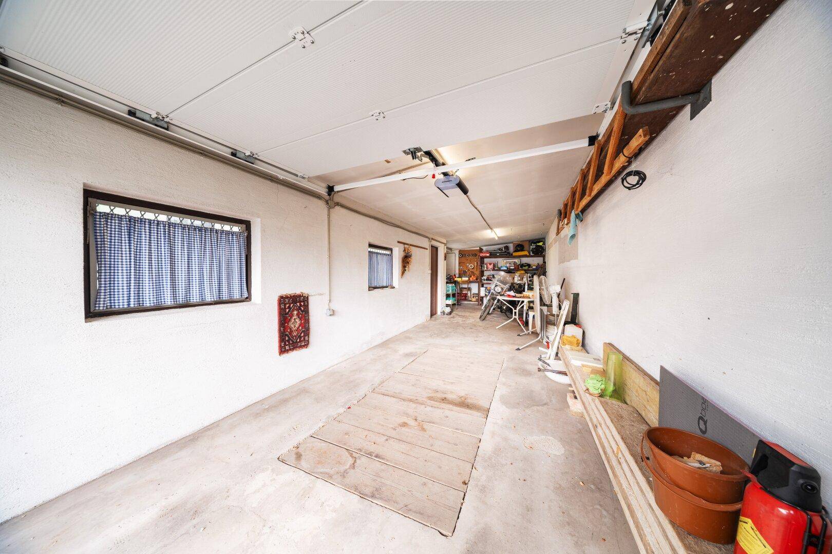 Geräumige Garage mit viel Stauraum, Werkzeugen und Betonboden.