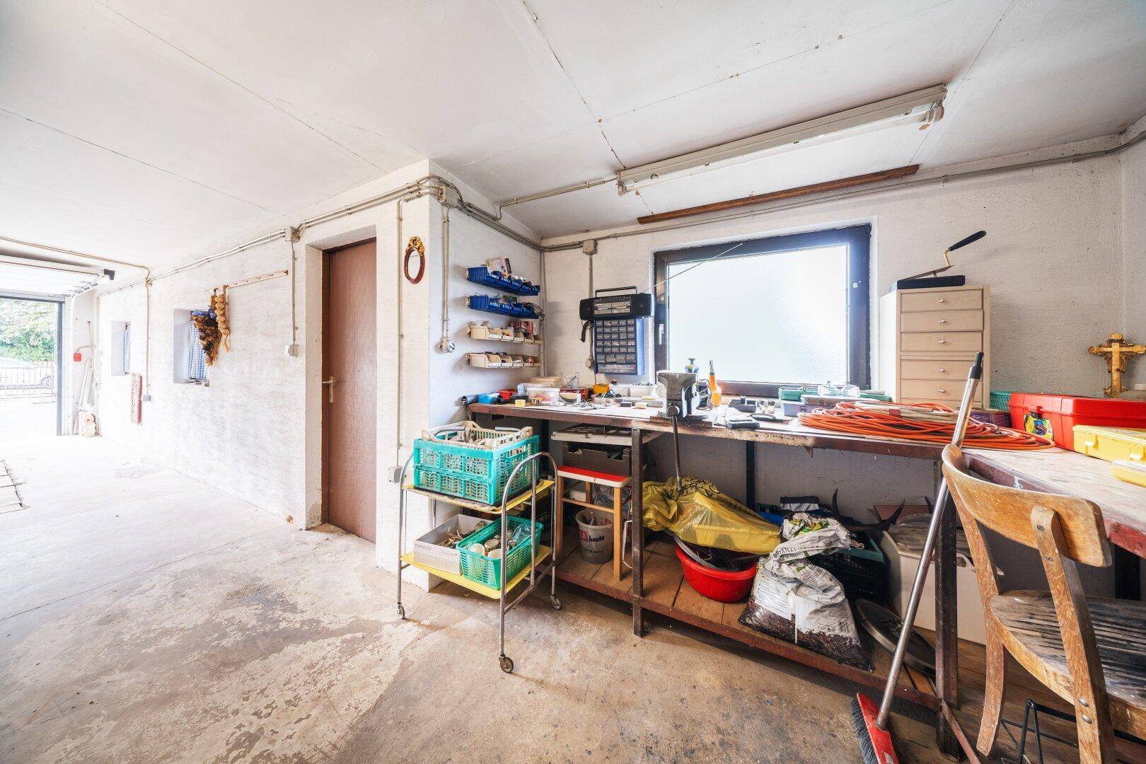 Werkstattbereich mit großem Fenster, Werkbank und verschiedenen Utensilien.