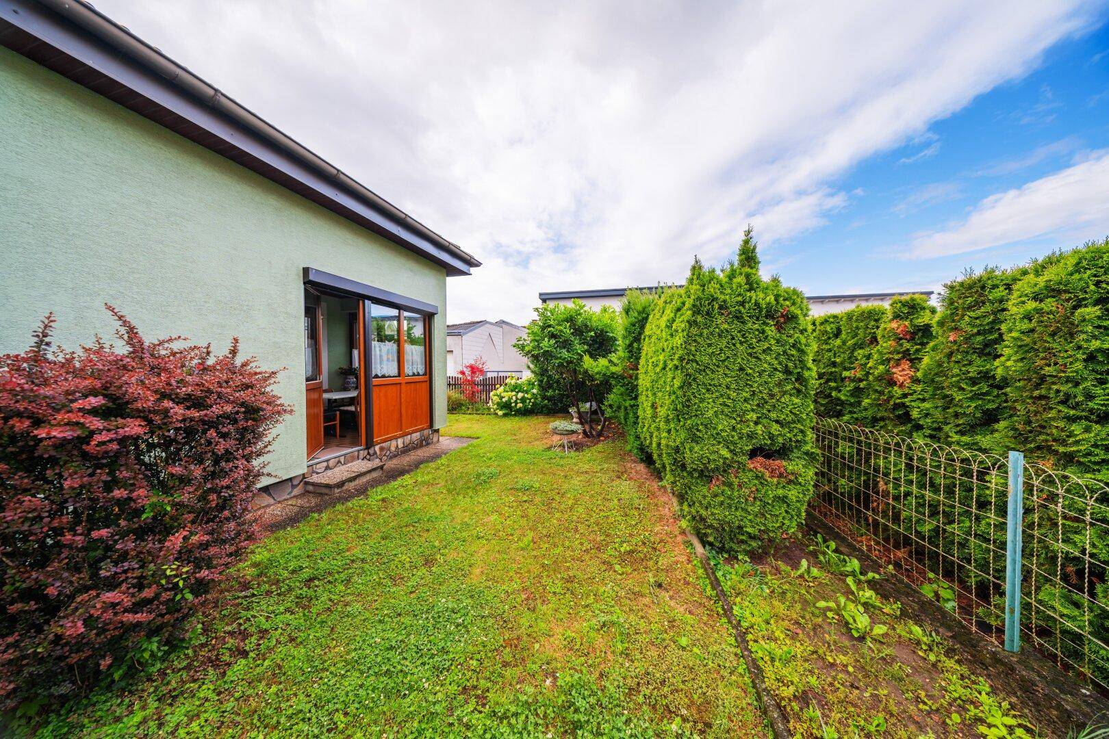 Hinterer Gartenbereich mit Rasenfläche und Zugang zum Haus.