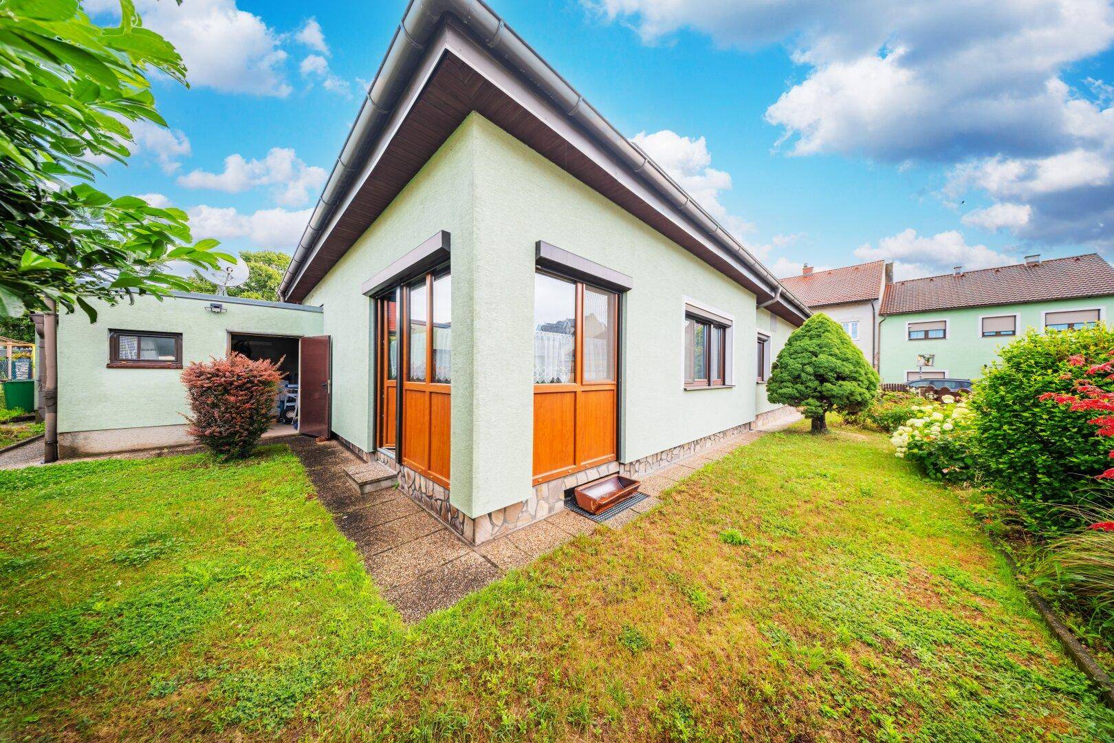Eckansicht des Hauses mit gepflegtem Garten und großen Fenstern.