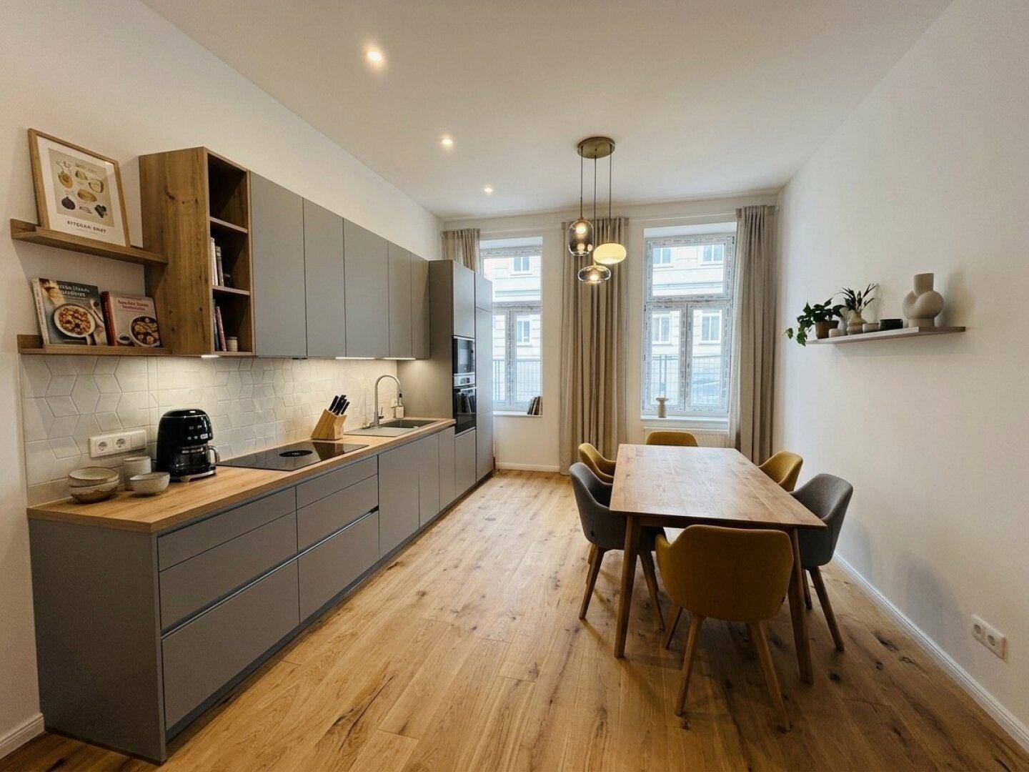 Moderne Küche mit grauen Schränken, Holzarbeitsplatte und Essbereich am Fenster.