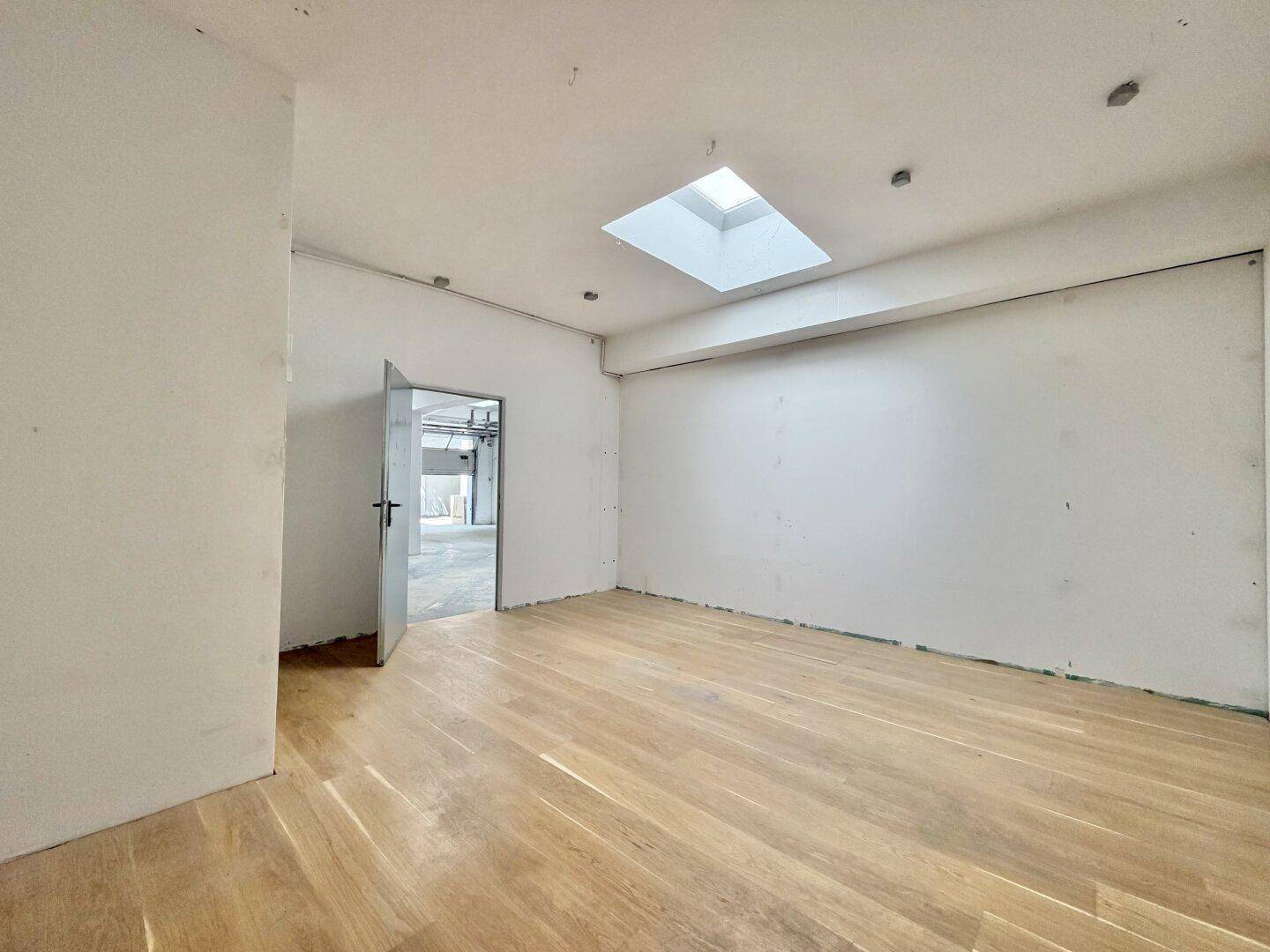 Kleiner Raum mit Holzplankenboden, weiß gestrichenen Wänden und einem Oberlicht.