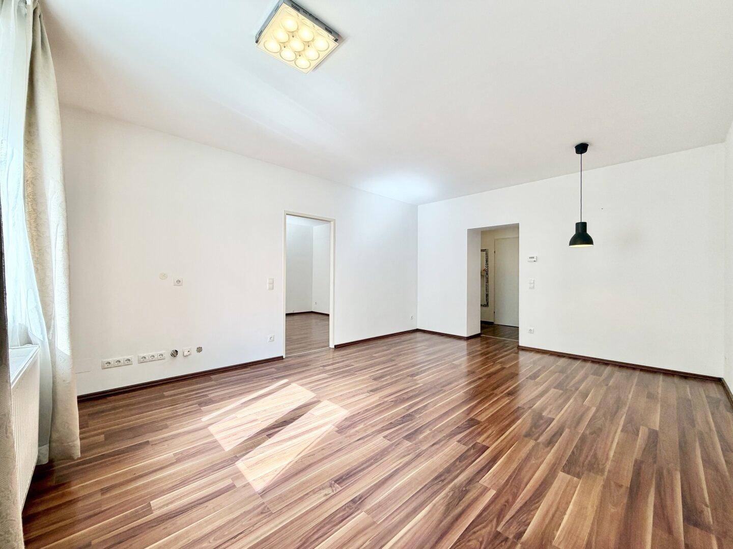 Geräumiges Zimmer mit Laminatboden und moderner Deckenleuchte, ideal für Wohnzwecke.