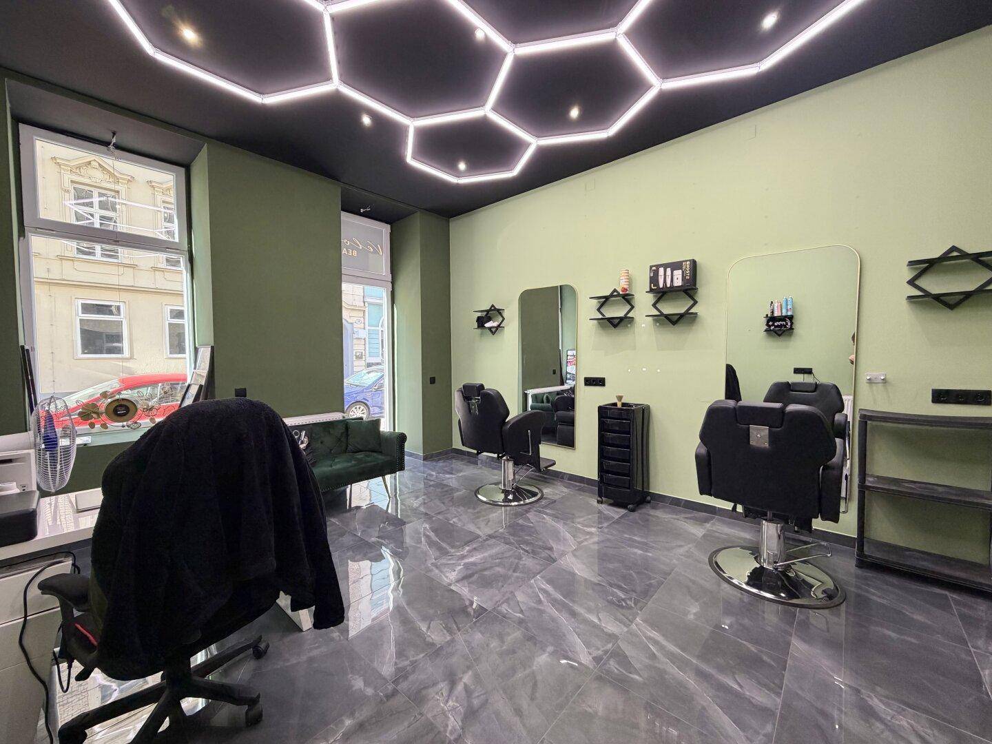 Innenansicht eines Friseursalons mit großen Schaufenstern, modernen Stühlen und einer einzigartigen Deckenbeleuchtung.