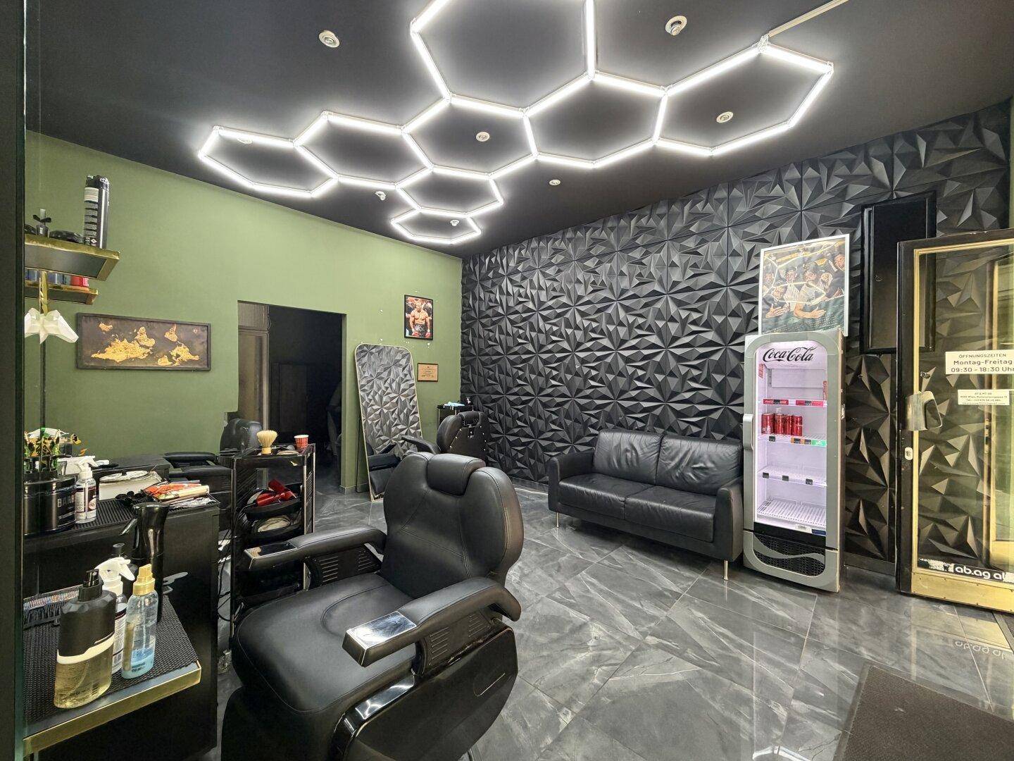 Innenansicht eines modernen Friseursalons mit 3D-Wandpaneelen, dunklen Fliesen und auffälliger Deckenbeleuchtung.