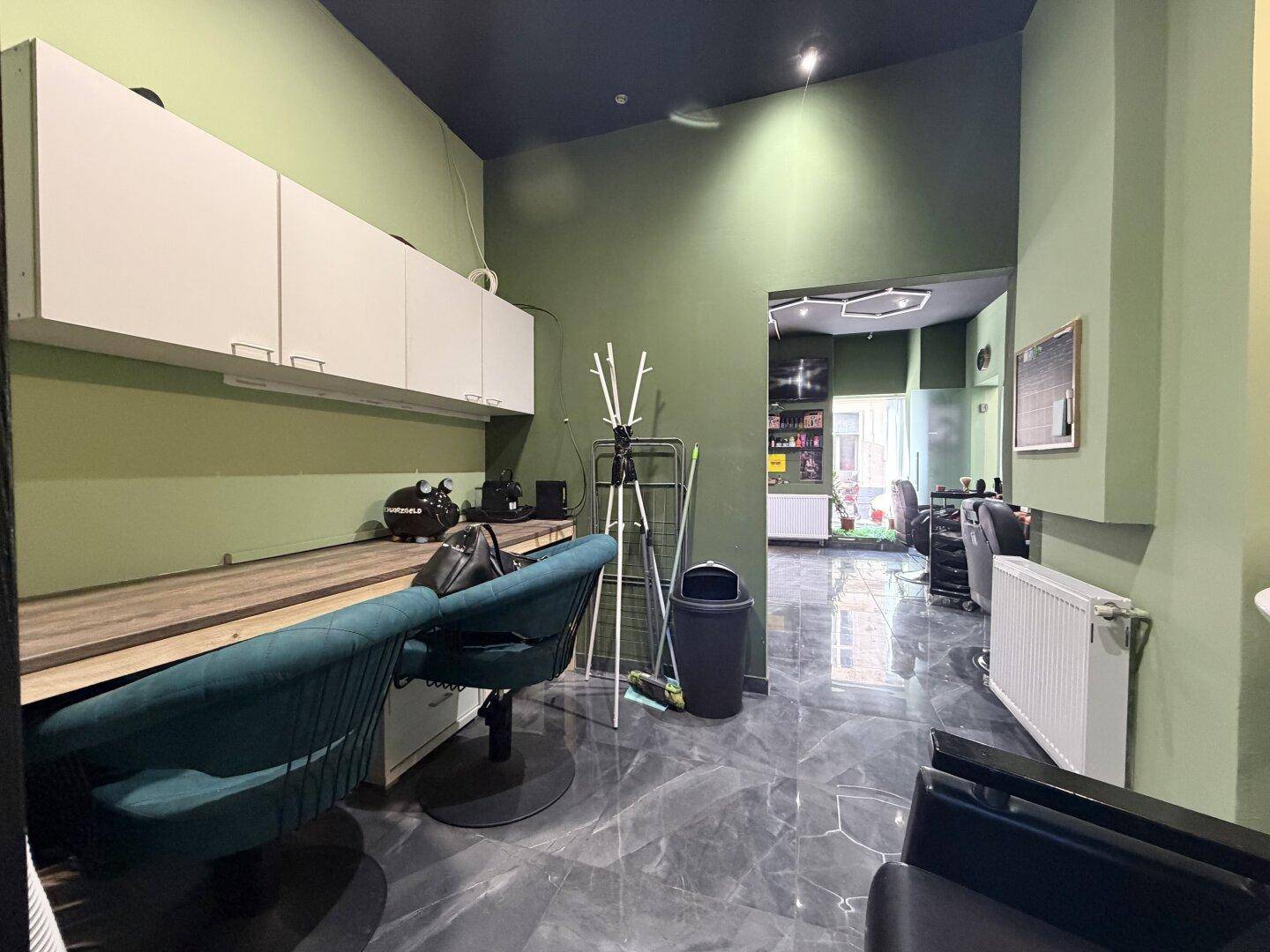 Waschbereich im Friseursalon mit dunklen Fliesen, weißen Hängeschränken und einem modernen Design.