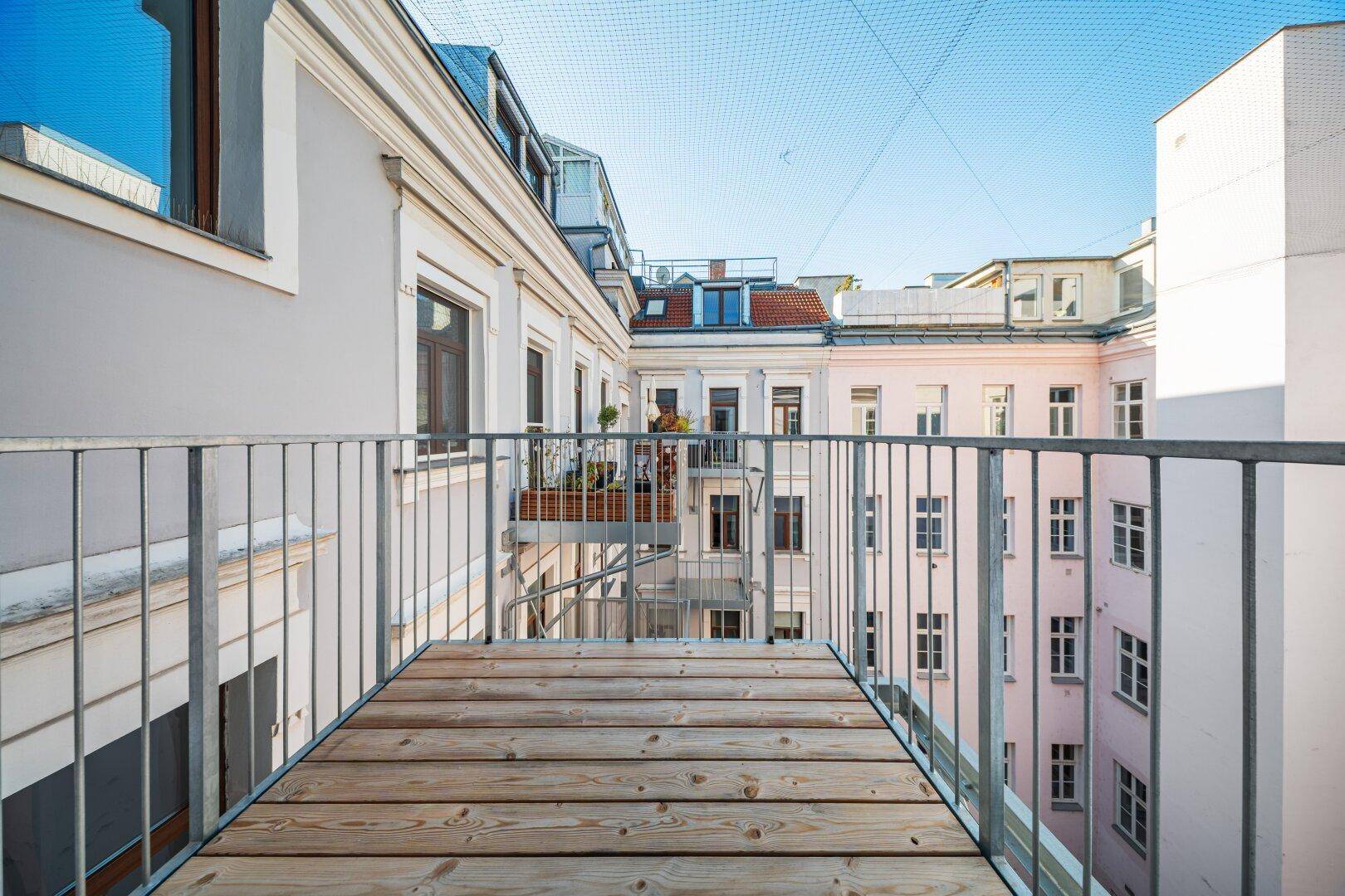 Kleiner Balkon mit Holzplanken und Blick auf den ruhigen Innenhof, ideal zum Entspannen.