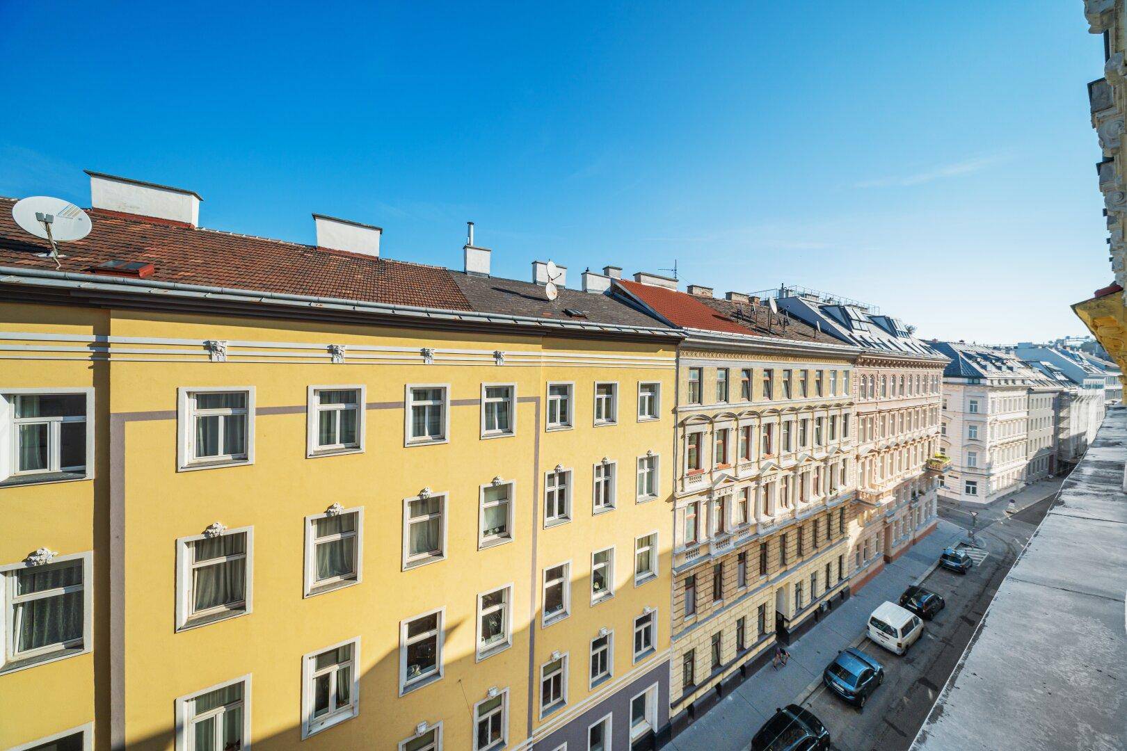 Ansicht einer gelben Wohnhausfassade mit zahlreichen Fenstern und traditioneller Architektur.
