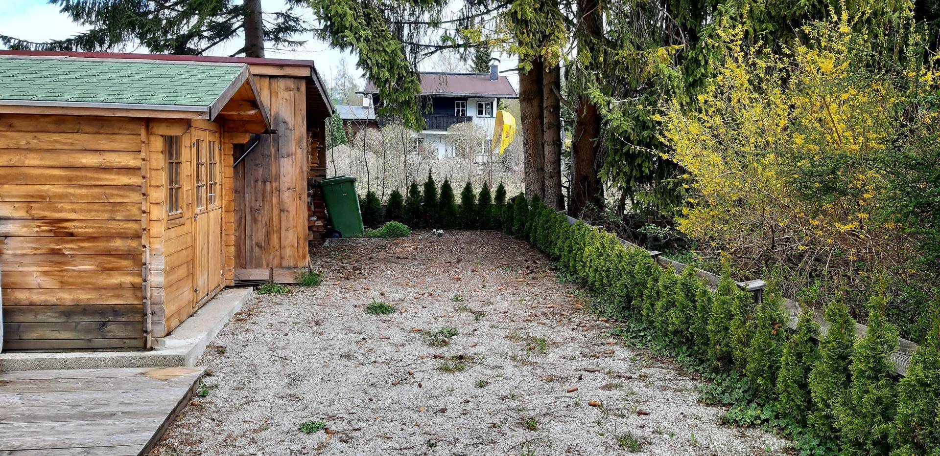 Gartenbereich mit Kiesfläche, gepflegter Hecke und Blick auf die Umgebung.