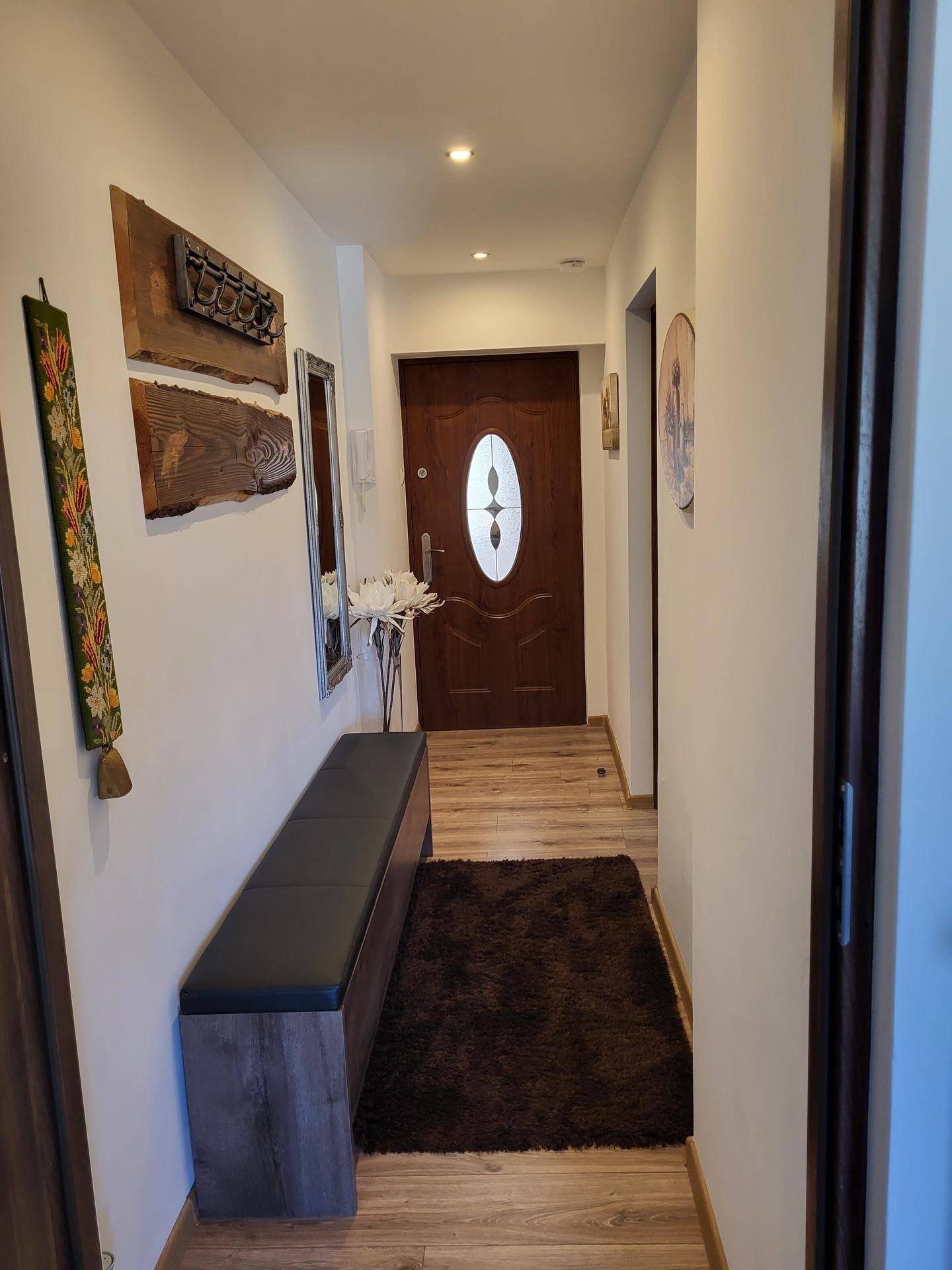 Heller Flur mit Holzboden, Garderobe und einer Sitzbank, die zum Verweilen einlädt.