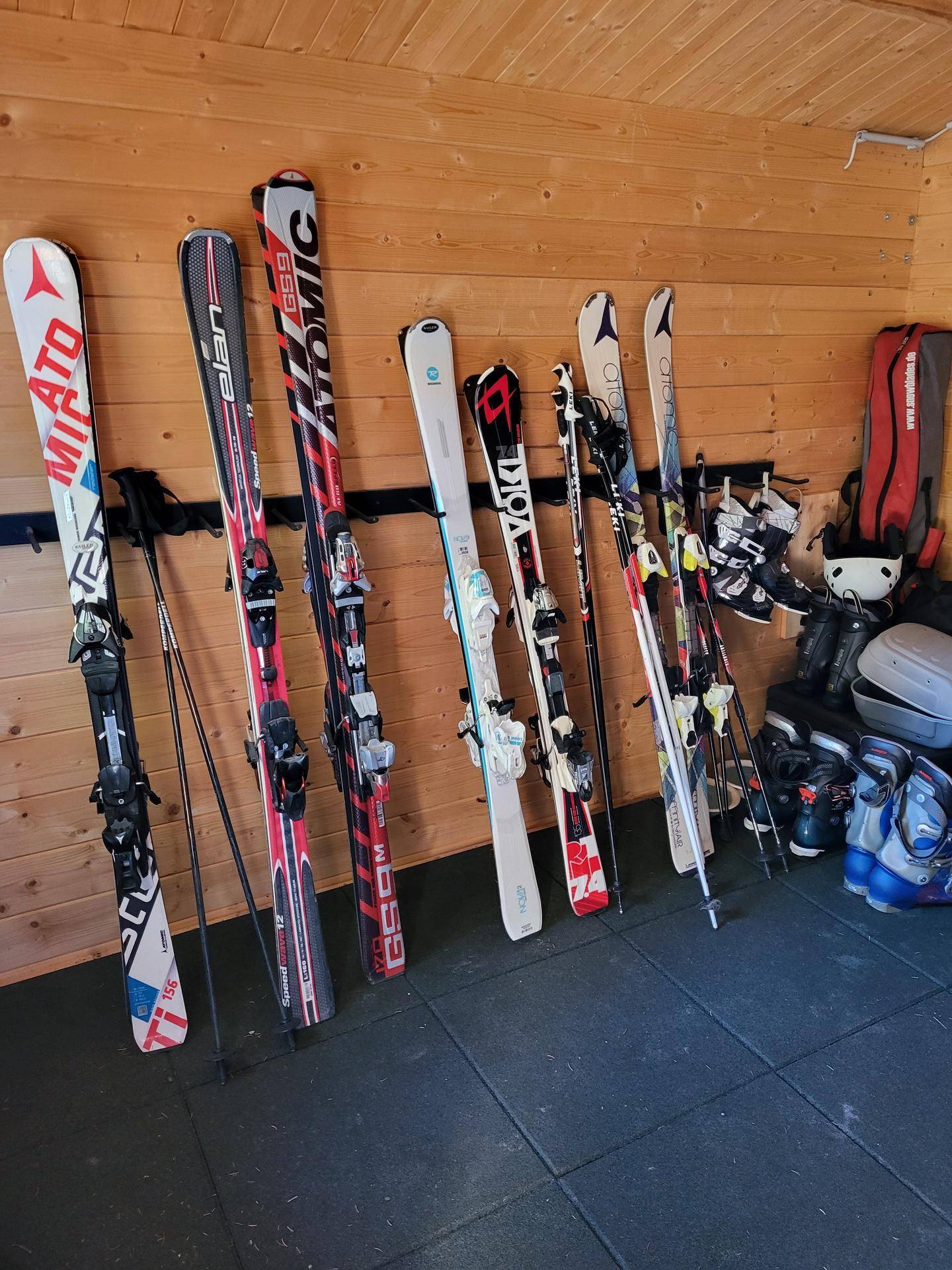 Skiausrüstung und Skischuhe ordentlich in einem Holzraum gelagert.