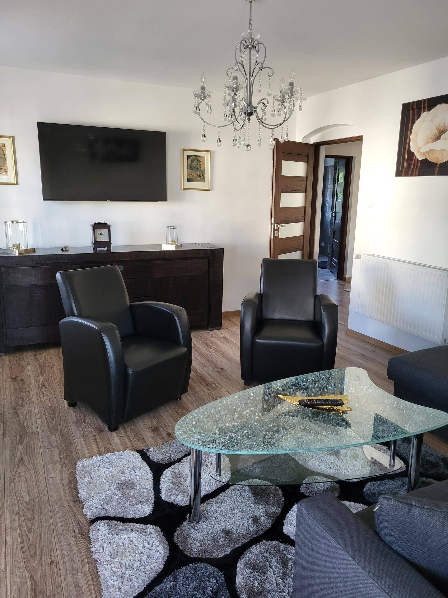 Elegantes Wohnzimmer mit Ledersesseln, Couchtisch und Fernseher an der Wand.