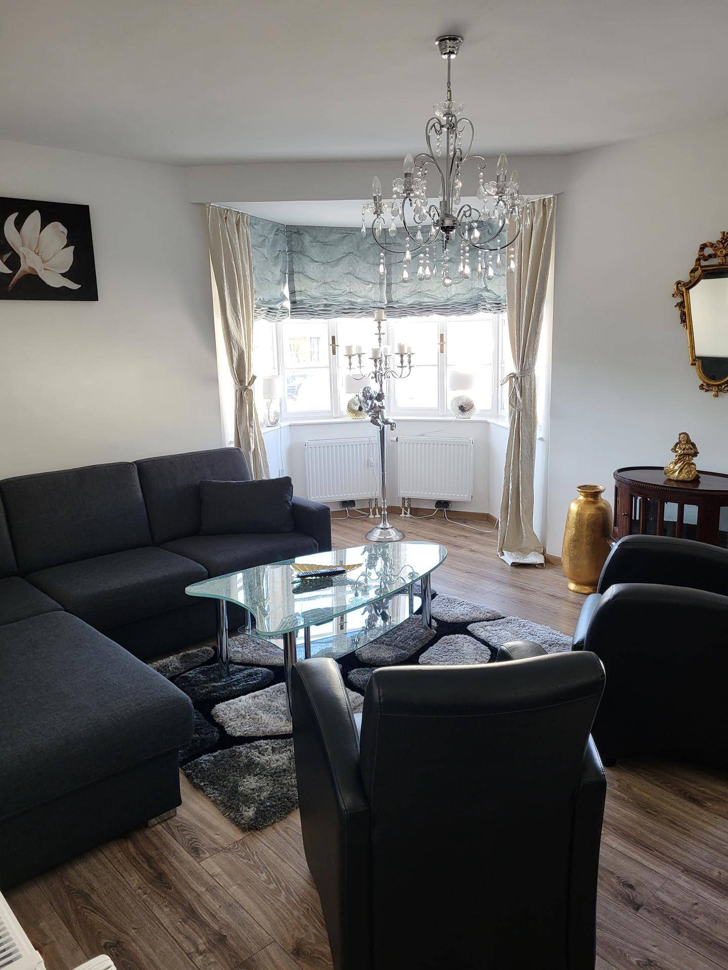 Elegantes Wohnzimmer mit großem Sofa, Couchtisch und Kronleuchter, hell und geräumig.