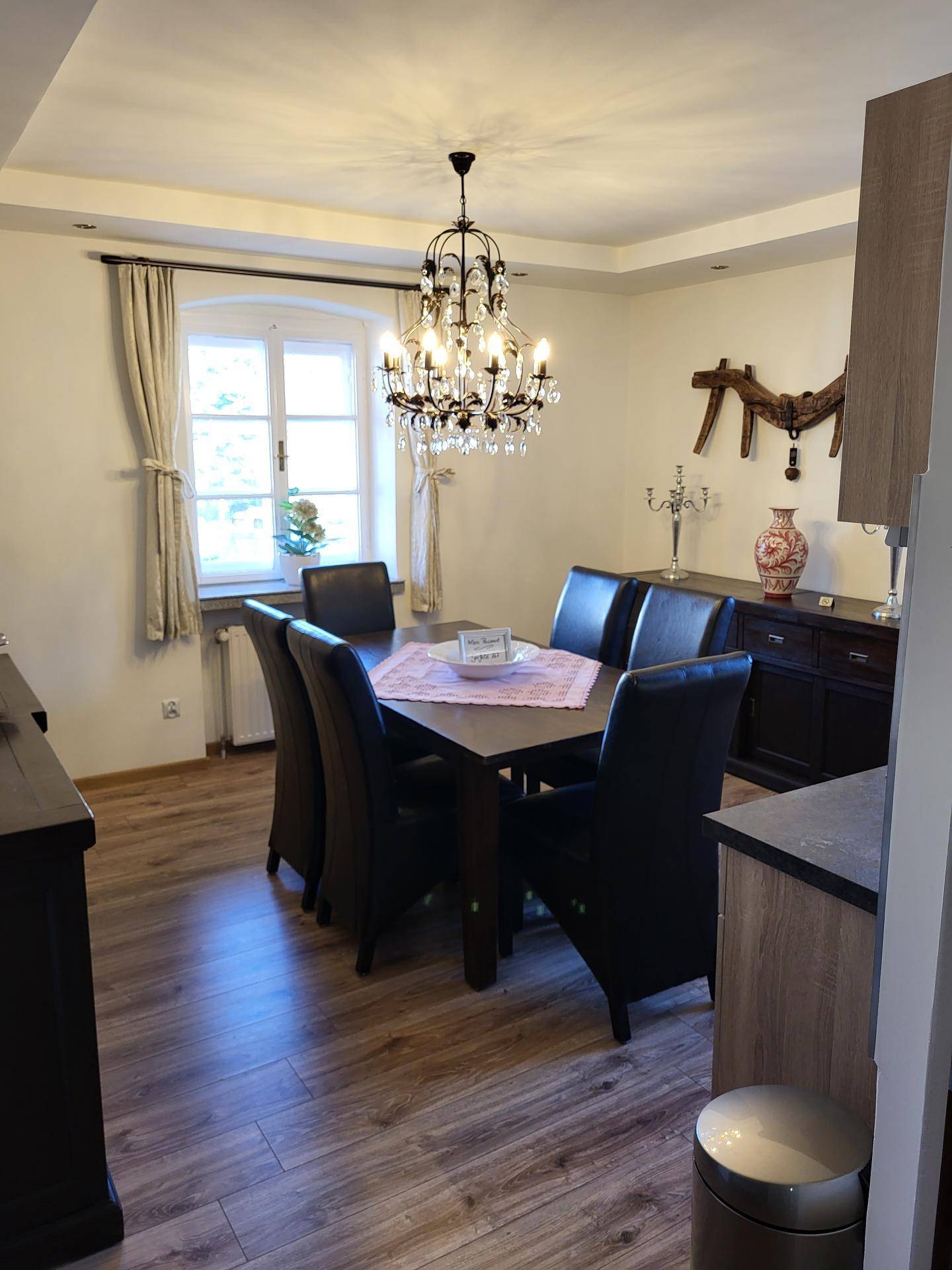 Stilvolles Esszimmer mit großem Holztisch, Lederstühlen und einem eleganten Kronleuchter.