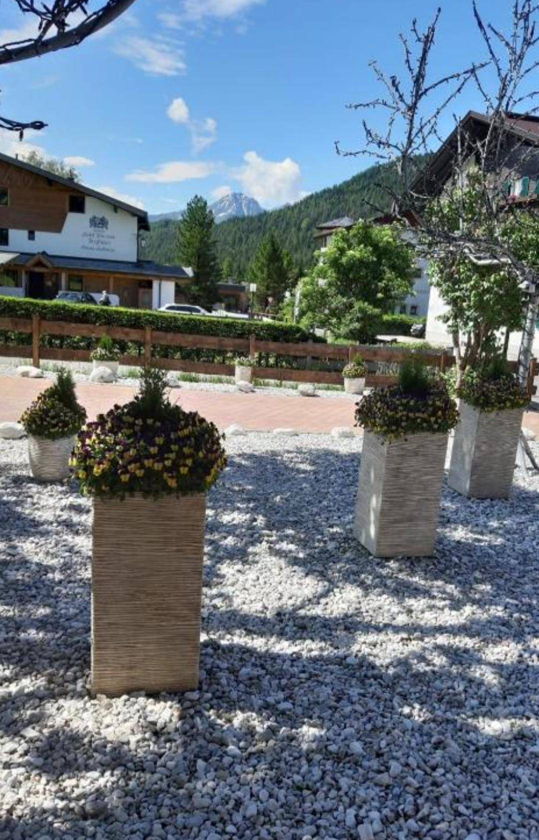 Dekorativer Vorgartenbereich mit Blumenkübeln und weitem Blick auf die umliegende Berglandschaft.