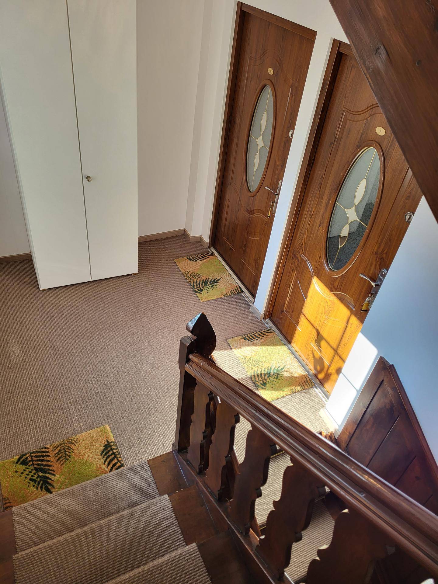 Treppenhaus mit Teppichboden und Holzgeländer, das zu den oberen Etagen führt.